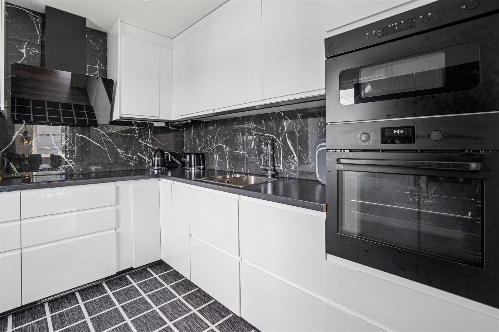 Slette fronter med skjulte håndtak og integrerte hvitevarer som komfyr, plateopp, micro og oppvaskamskin. Det er frittstående side by side kjøleskap Galleribilde