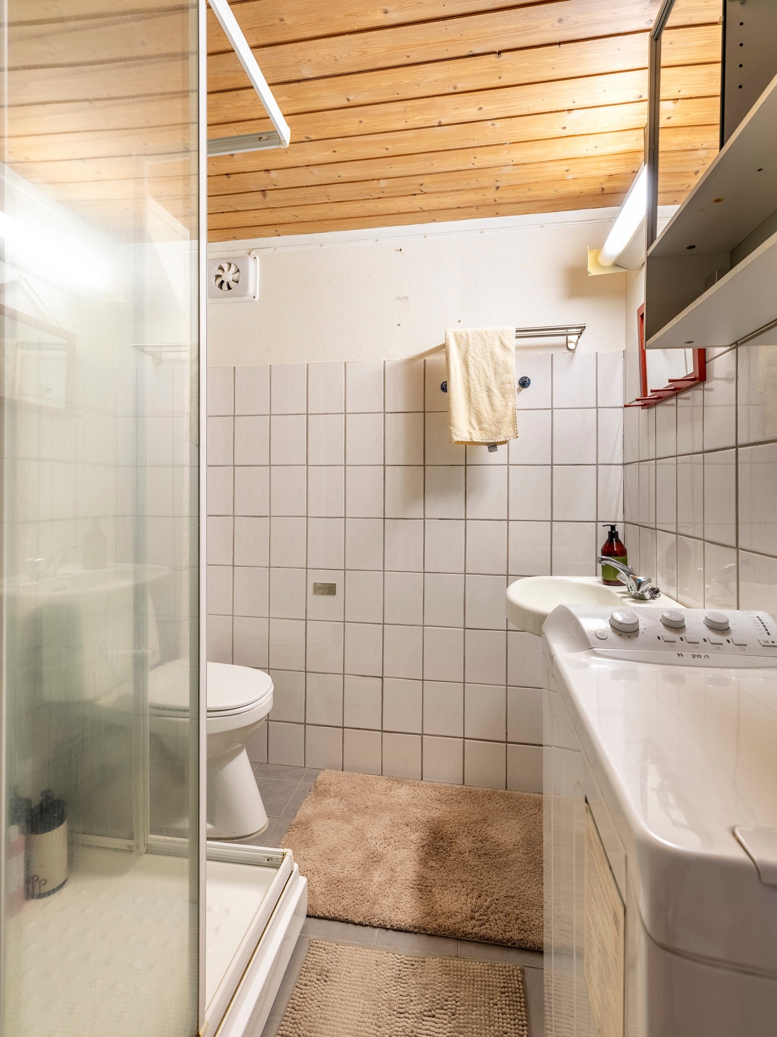 Badet har flislagt gulv utstyrt med elektriske varmekabler, mens veggene har fliser kombinert med malt tapet/strie. Galleribilde