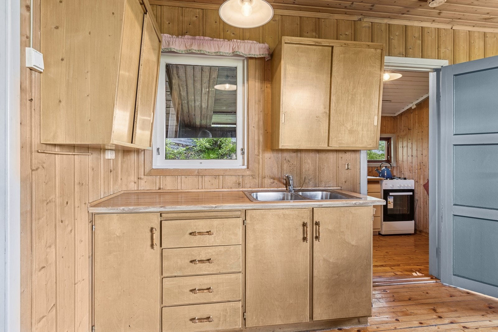 Stuen har en enkel kjøkkenkrok med både over- og underskap, samt en benkeplate med kjøkkenkran og dobbel vaskekum. Galleribilde