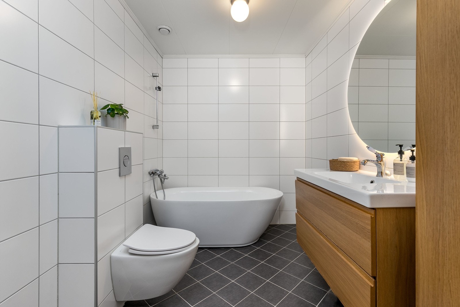 Smakfullt hovedbad i boligens 1. etasje, nytt i 2011. Badet har flislagte overflater og varmekabler i gulv. Innredningen består av stilrent servantmøblement i eik med 2 skuffer, tilhørende høyskap, samt vegghengt toalett. Galleribilde