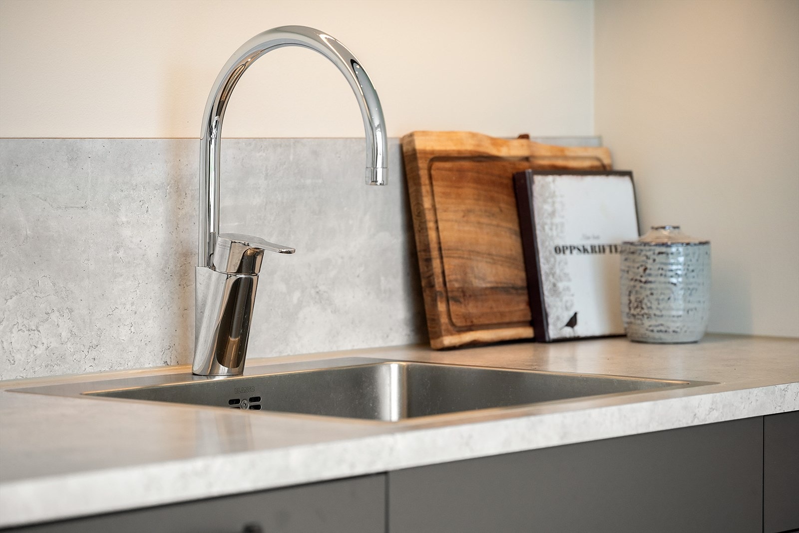 Nedfelt i benkeplaten er det en dyp stålvask og i våtsonen på veggen bak er det fuktbestandig veggplate. Galleribilde