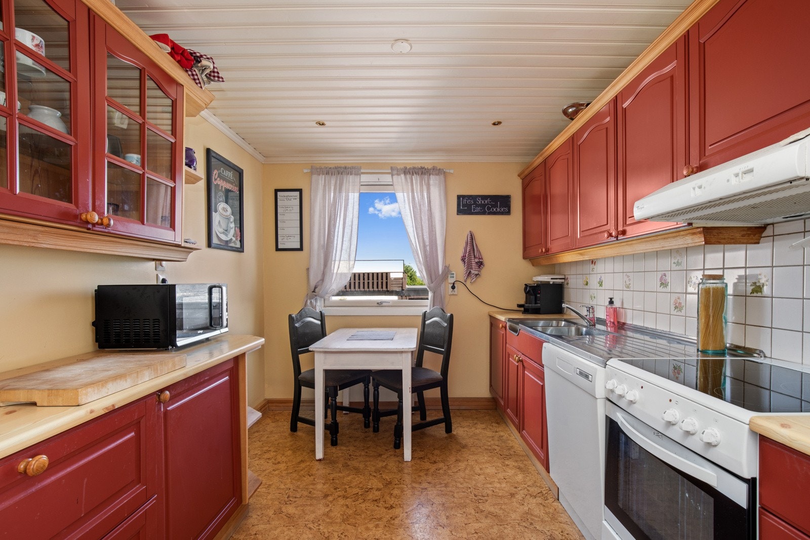 Kjøkkenet har innredning langs to vegger og plass til spisebord ved vinduet. Galleribilde