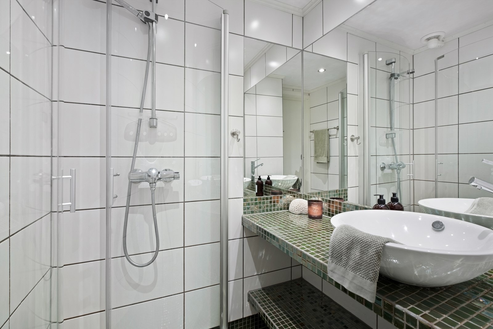 Det flislagte badet er praktisk anvendt og byr på innfellbare dusjdører, samt innredet servant med rikelig oppbevaringsplass. Galleribilde