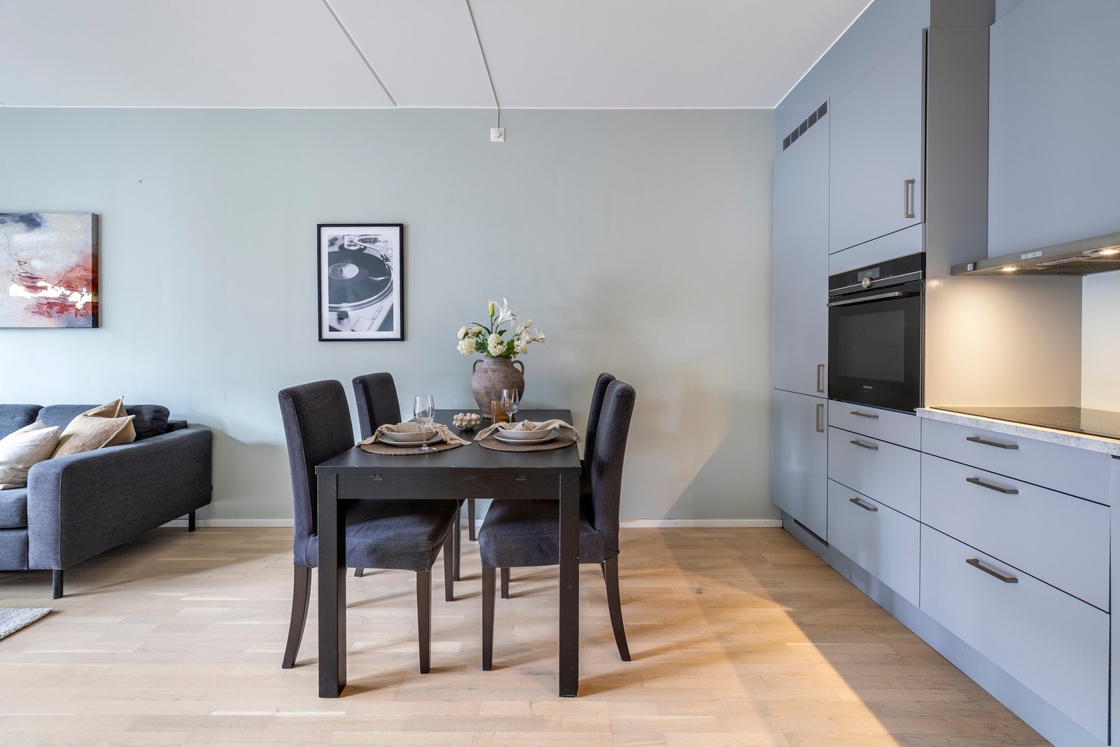 Kjøkkeninnredningen er levert av Sigdal, med stilfulle glatte fronter og laminert benkeplate med innfelt vask. Det er plass til et spisebord mellom kjøkken og stuedelen. Galleribilde