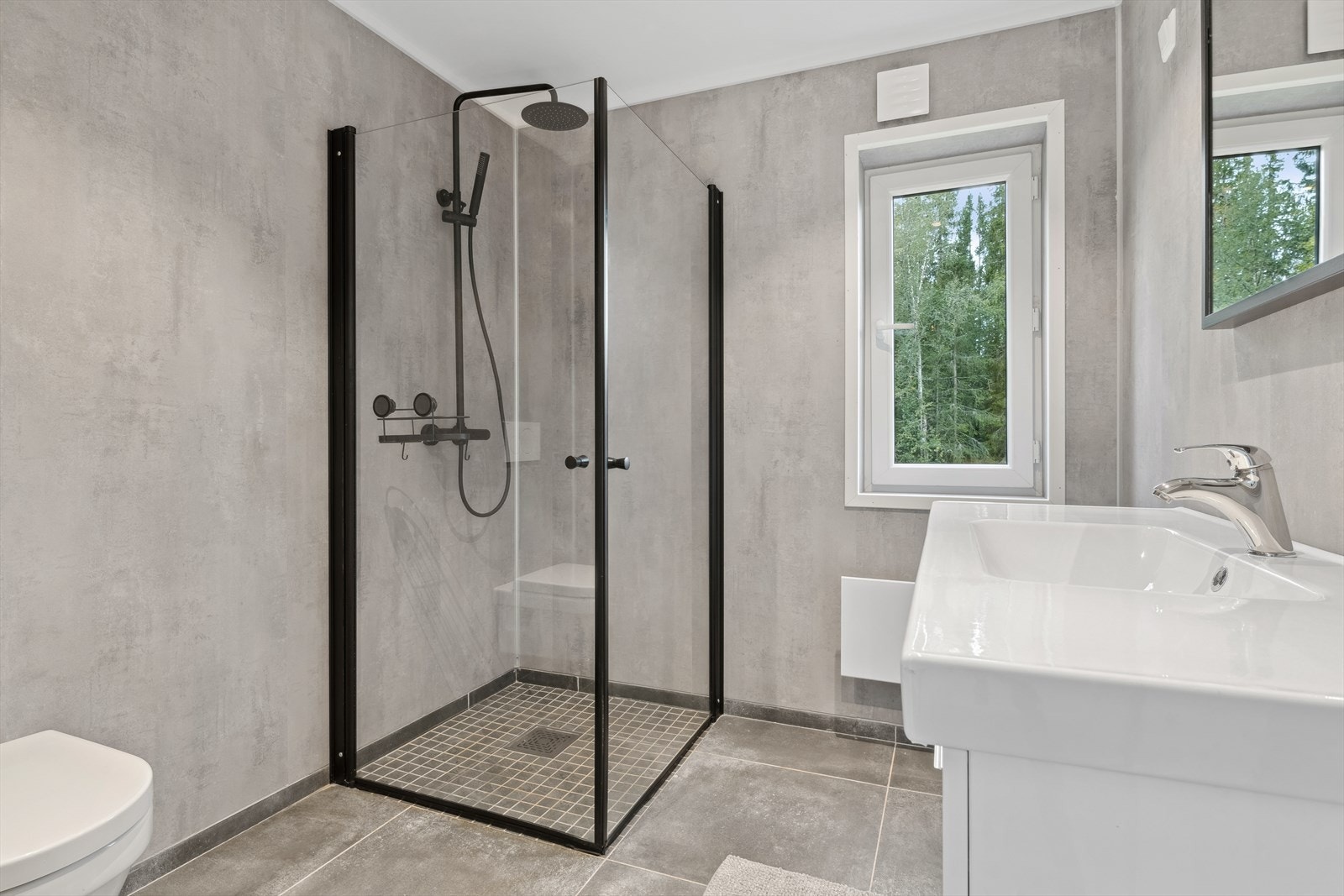 Pent bad fra ca 2020 med flis på gulv og våtromsplater på vegger. Downlights i himling. Panelovn. Galleribilde