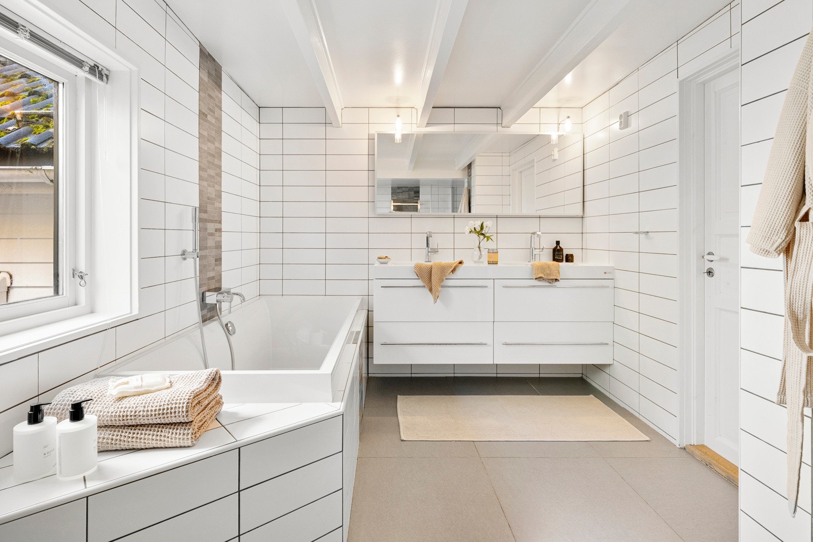 Badet i første etasje har flislagte overflater, moderne baderomsinnredning, badekar og stor dusjnisje. Galleribilde