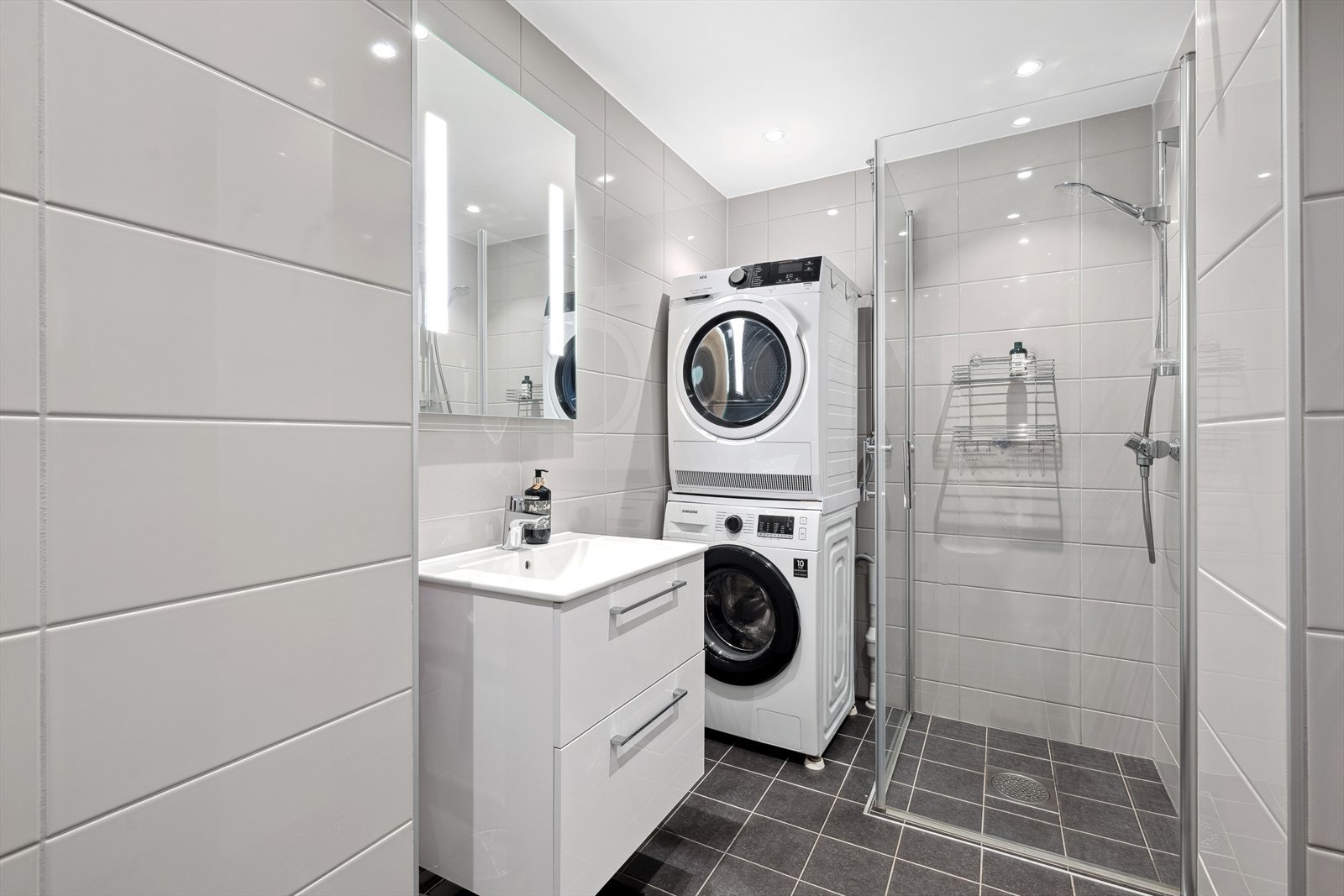 Lekkert flislagt bad fra 2021 med dusjnisje, pen innredning, vegghengt wc og opplegg for vaskemaskin. Galleribilde