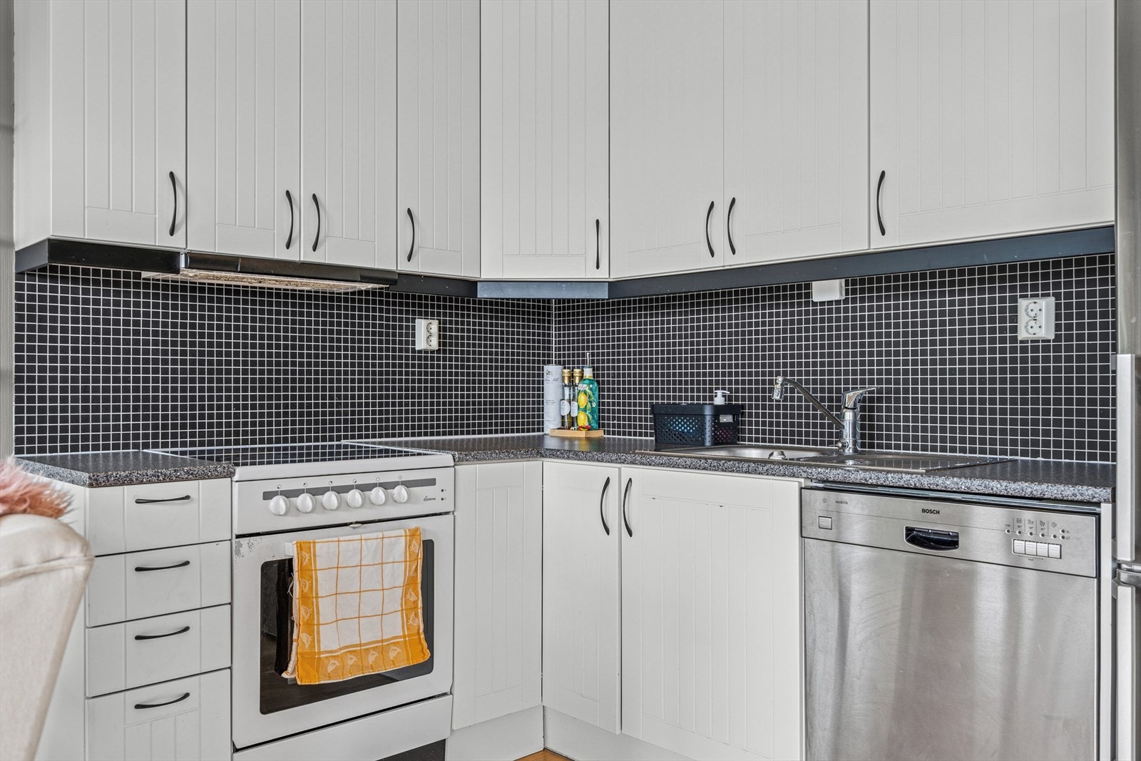 Det er fliser over benkeplate og lysarmatur under overskap. Galleribilde