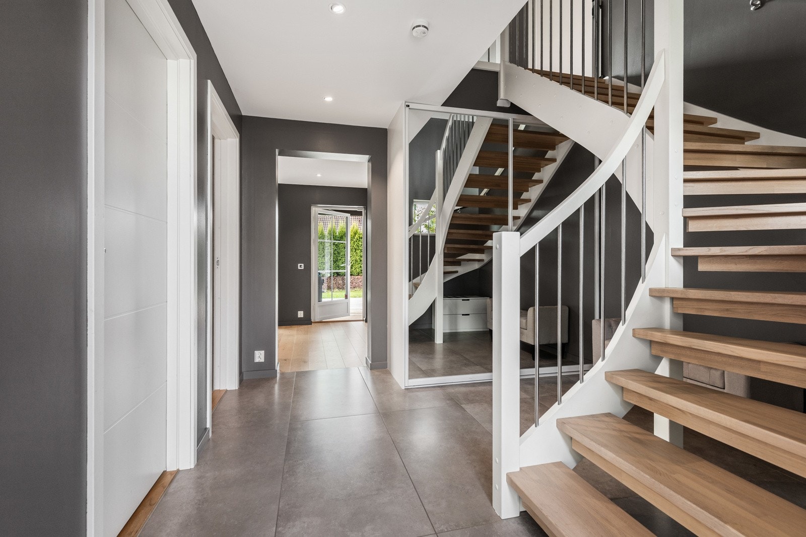 Lyst og romslig inngangsparti med moderne trapp og speil. Galleribilde