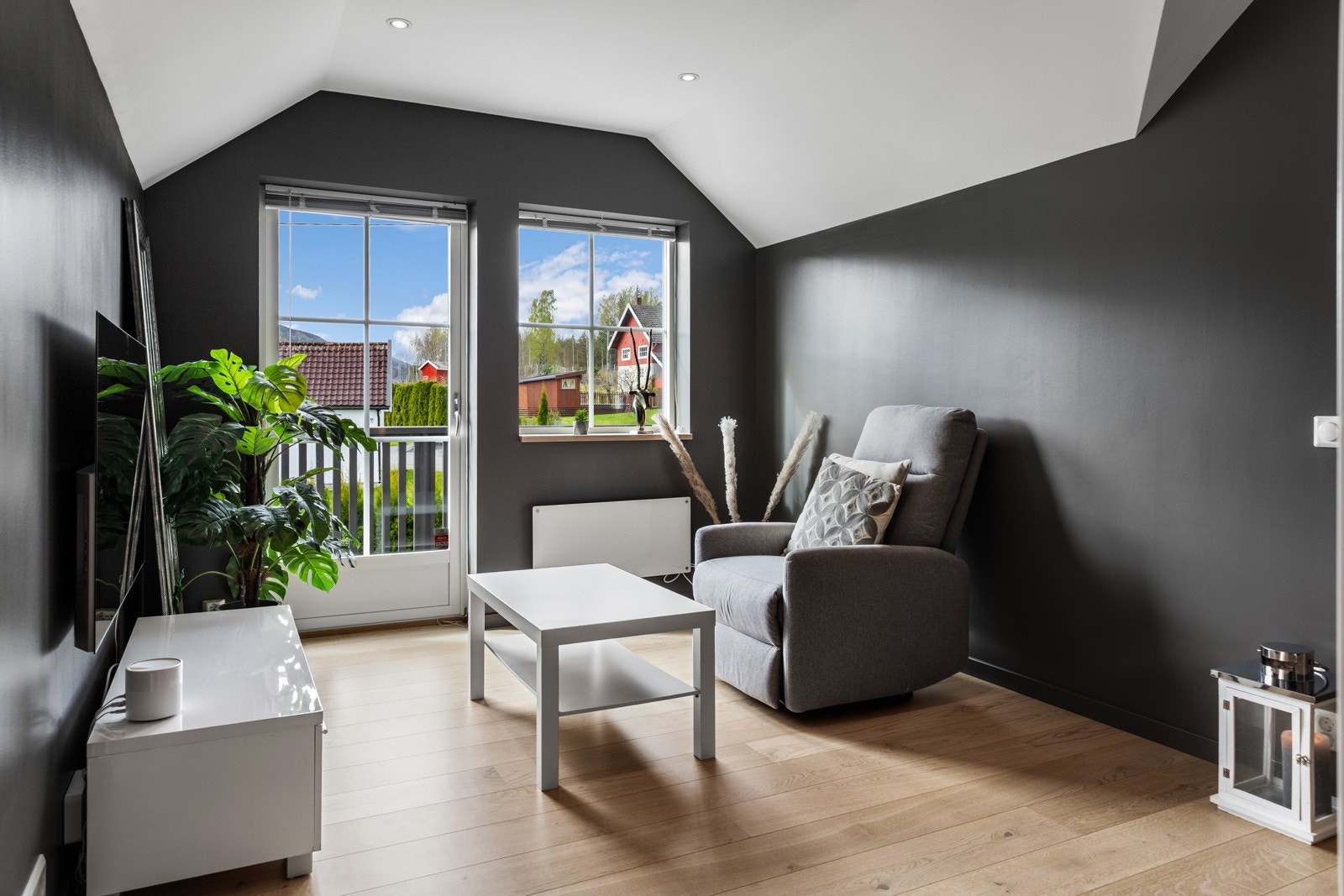 Lys stue med store vinduer, grå vegger og lys parkettgulv. Galleribilde