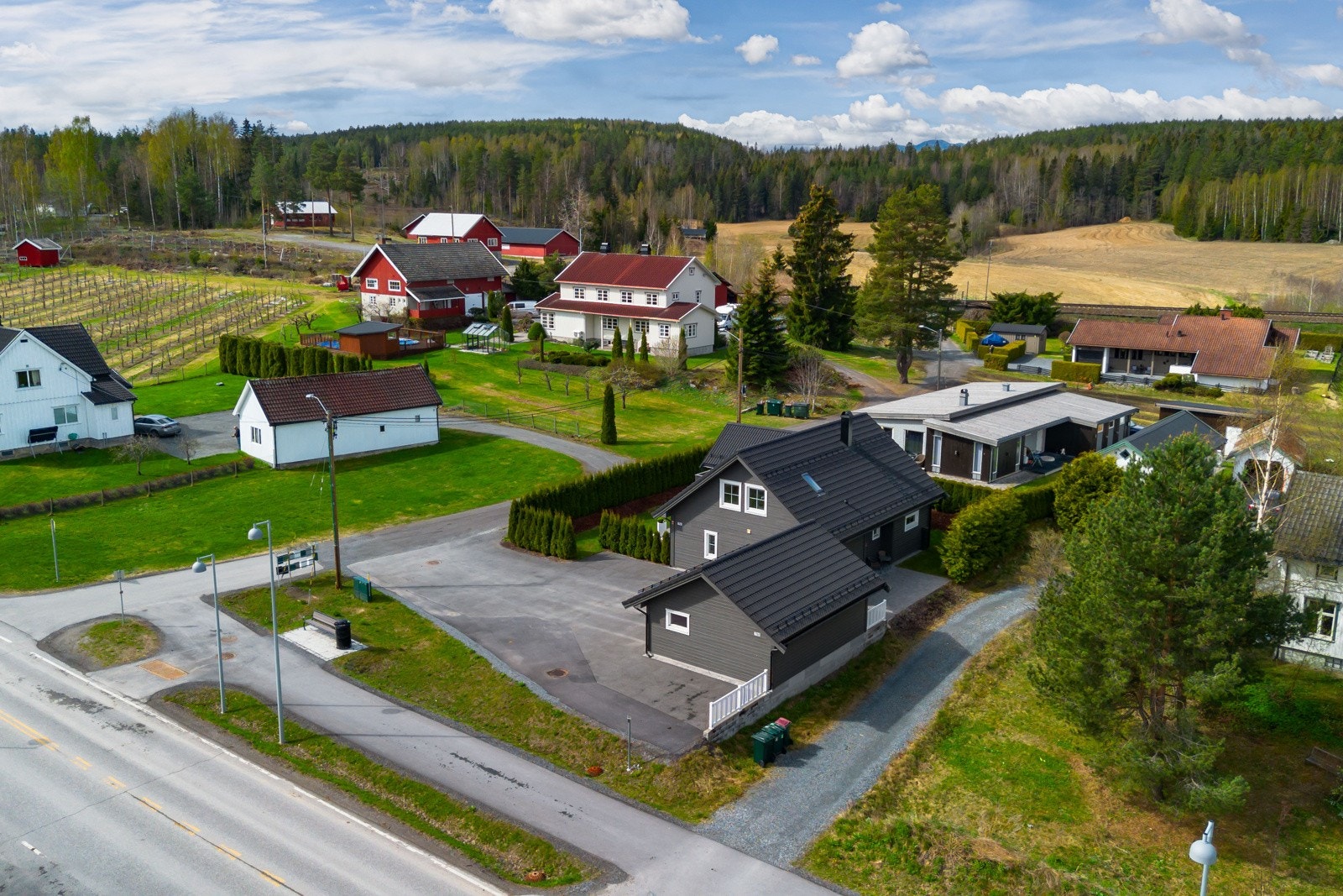 Boligen ligger i et landlig område med flere hus og gårder rundt, omgitt av skog og åkrer. Galleribilde