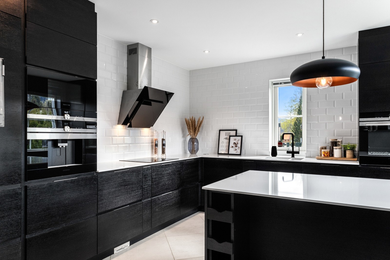 Moderne kjøkken med svarte skap, integrerte hvitevarer, hvite fliser og lys benkeplate. Galleribilde