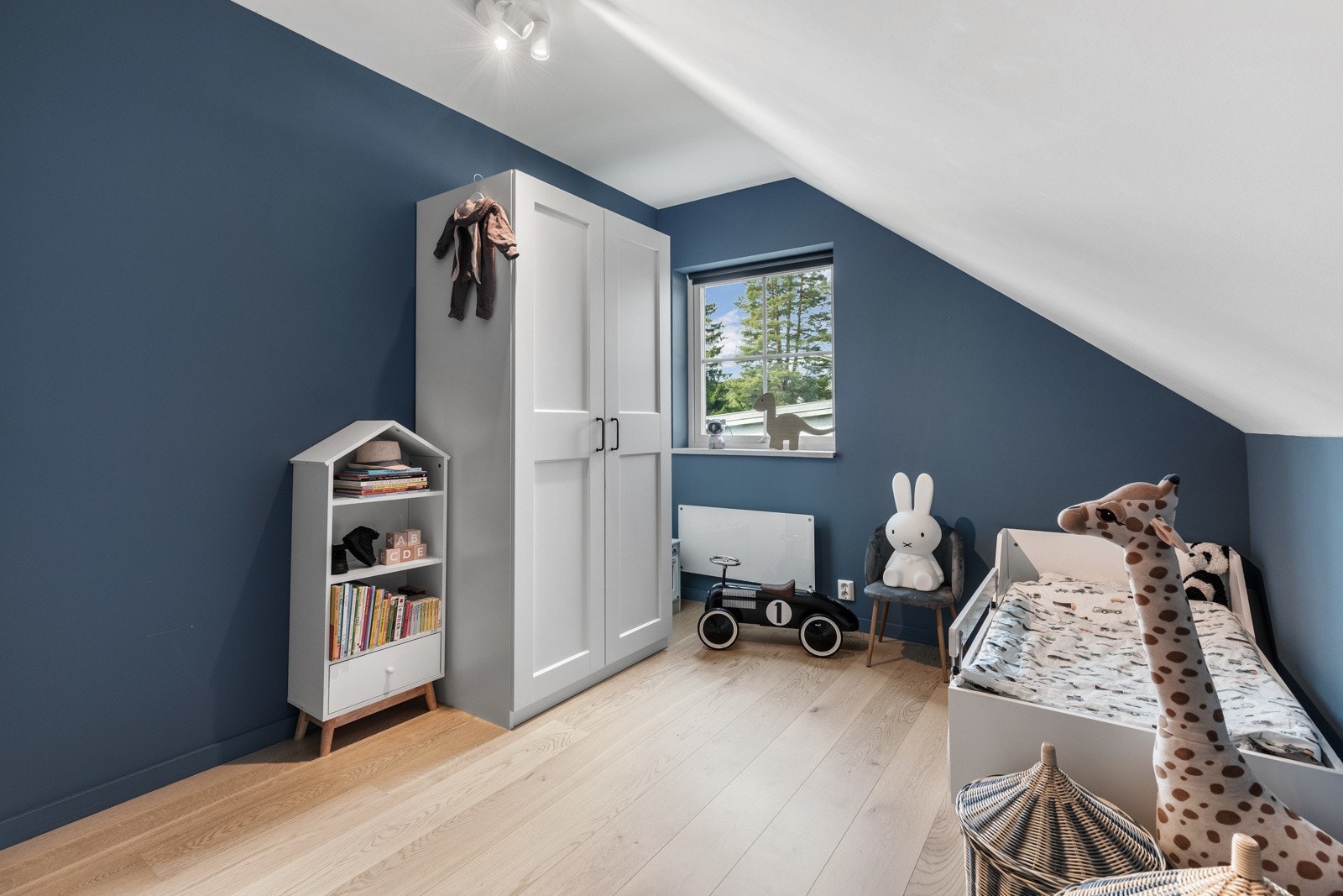 Barnerom med blå vegger, skråtak og garderobeskap. Galleribilde