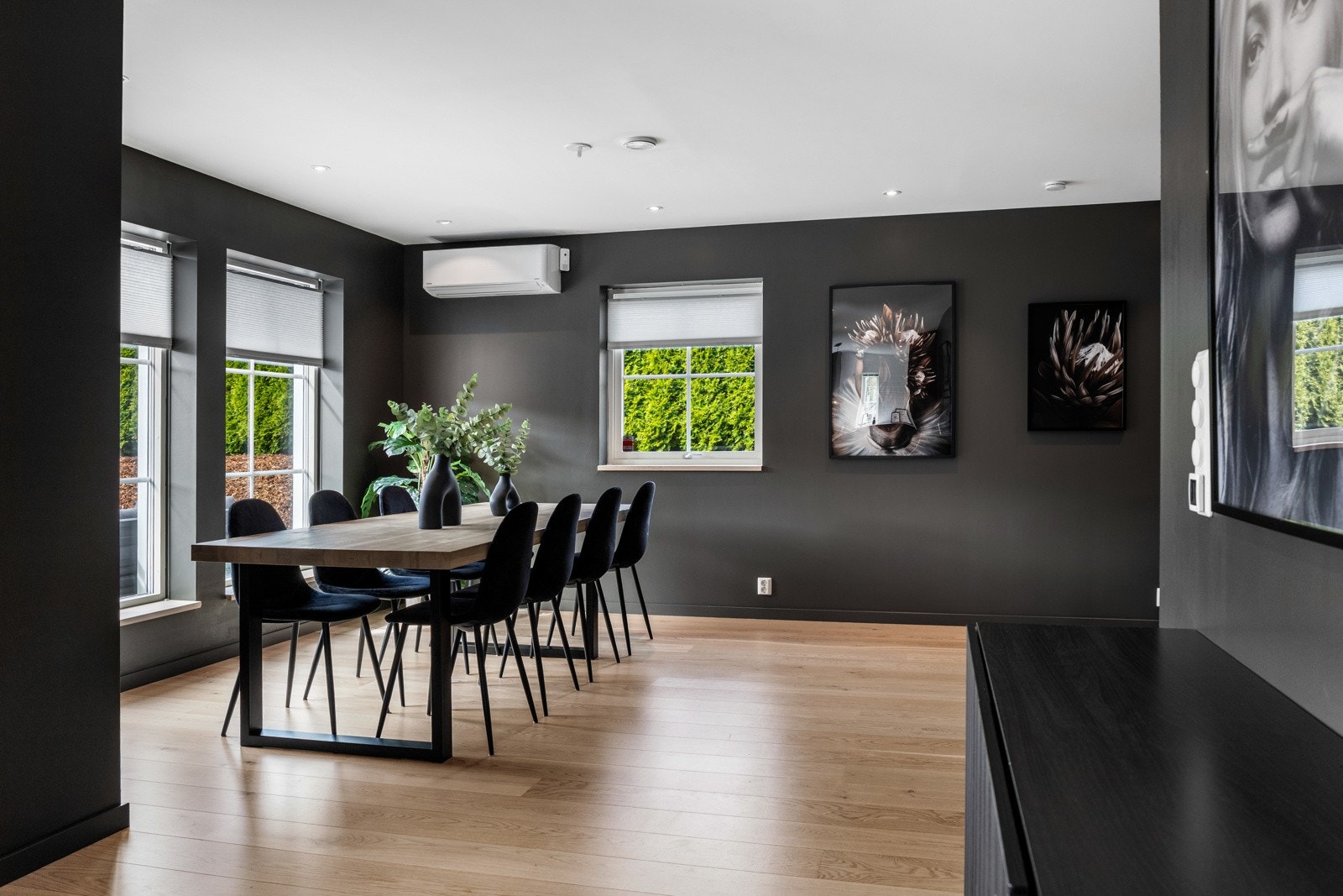Spisestue med store vinduer, mørke vegger og varmepumpe. Galleribilde