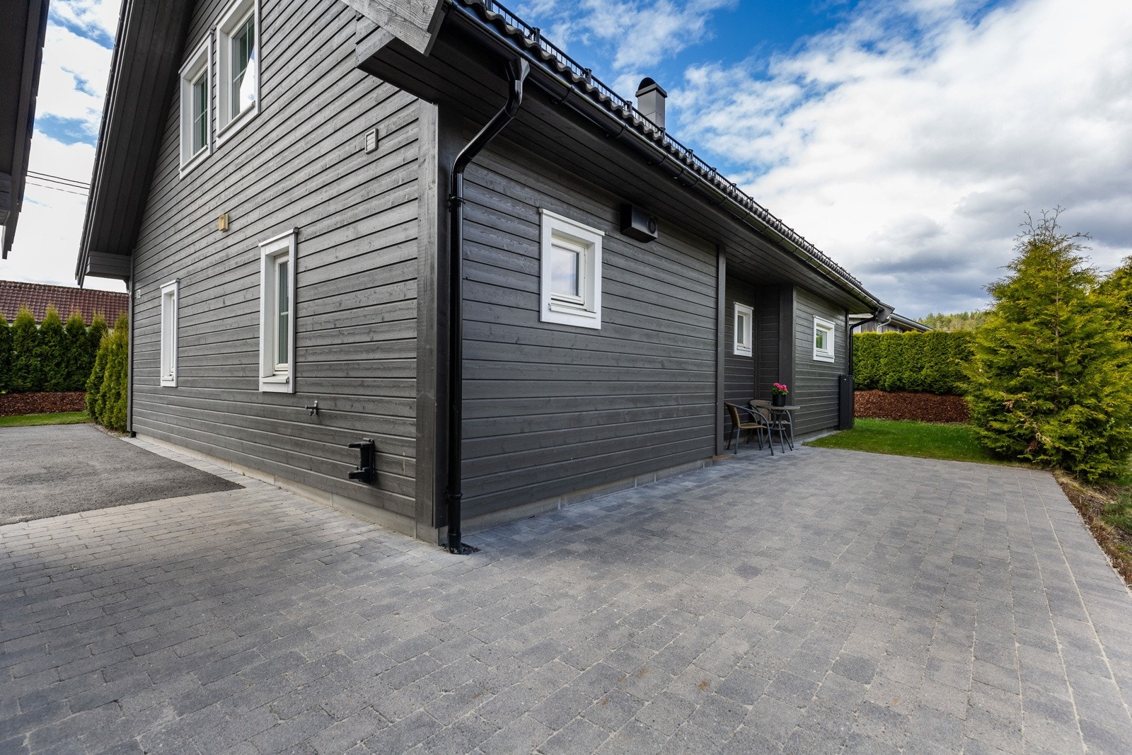 Moderne bolig med store vinduer og steinbelagt uteplass. Omgitt av velholdt hage og hekk. Galleribilde