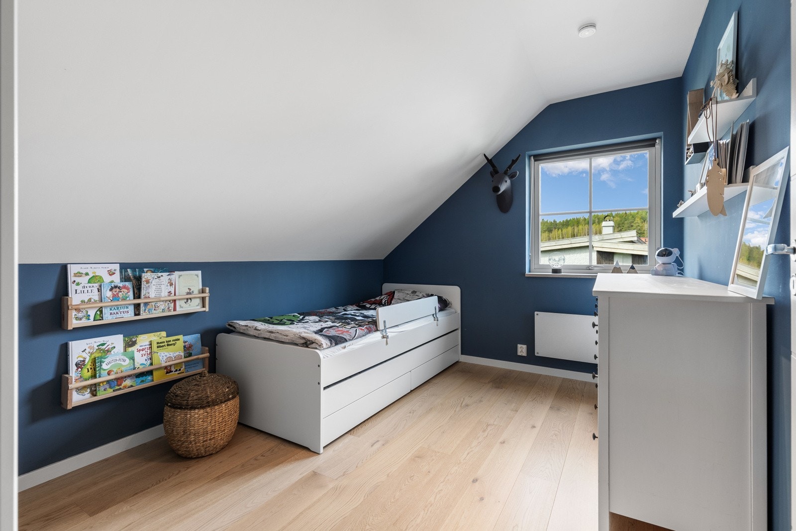 Lyst barnerom med skråtak, blå vegger og tregulv. Galleribilde