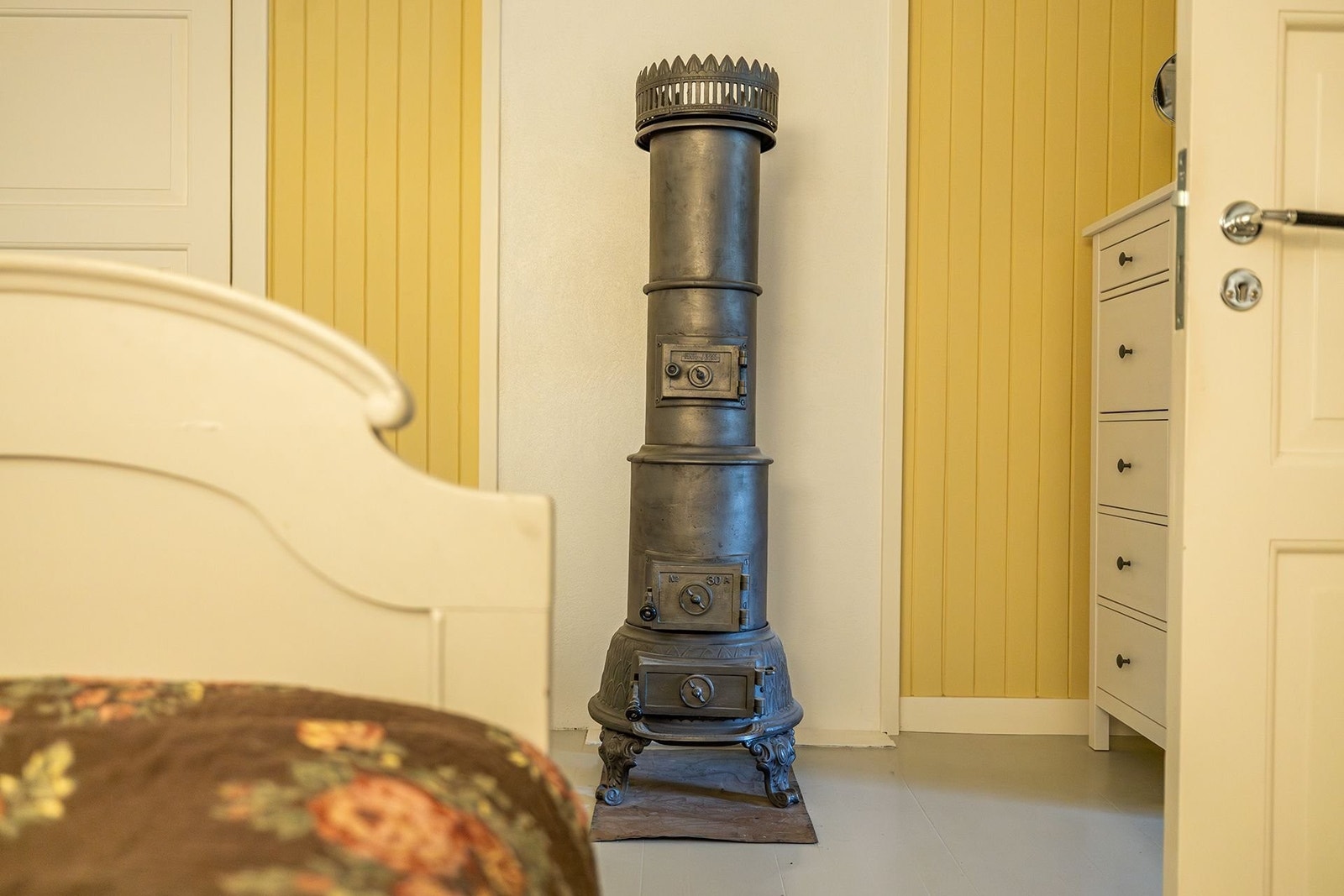 Restaurert søyleovn fra HamJern. (Her må gnistplate monteres før ovnen brukes, ellers er denne klar til bruk.) Tidsriktig dobbeltseng kan følge salget. Galleribilde