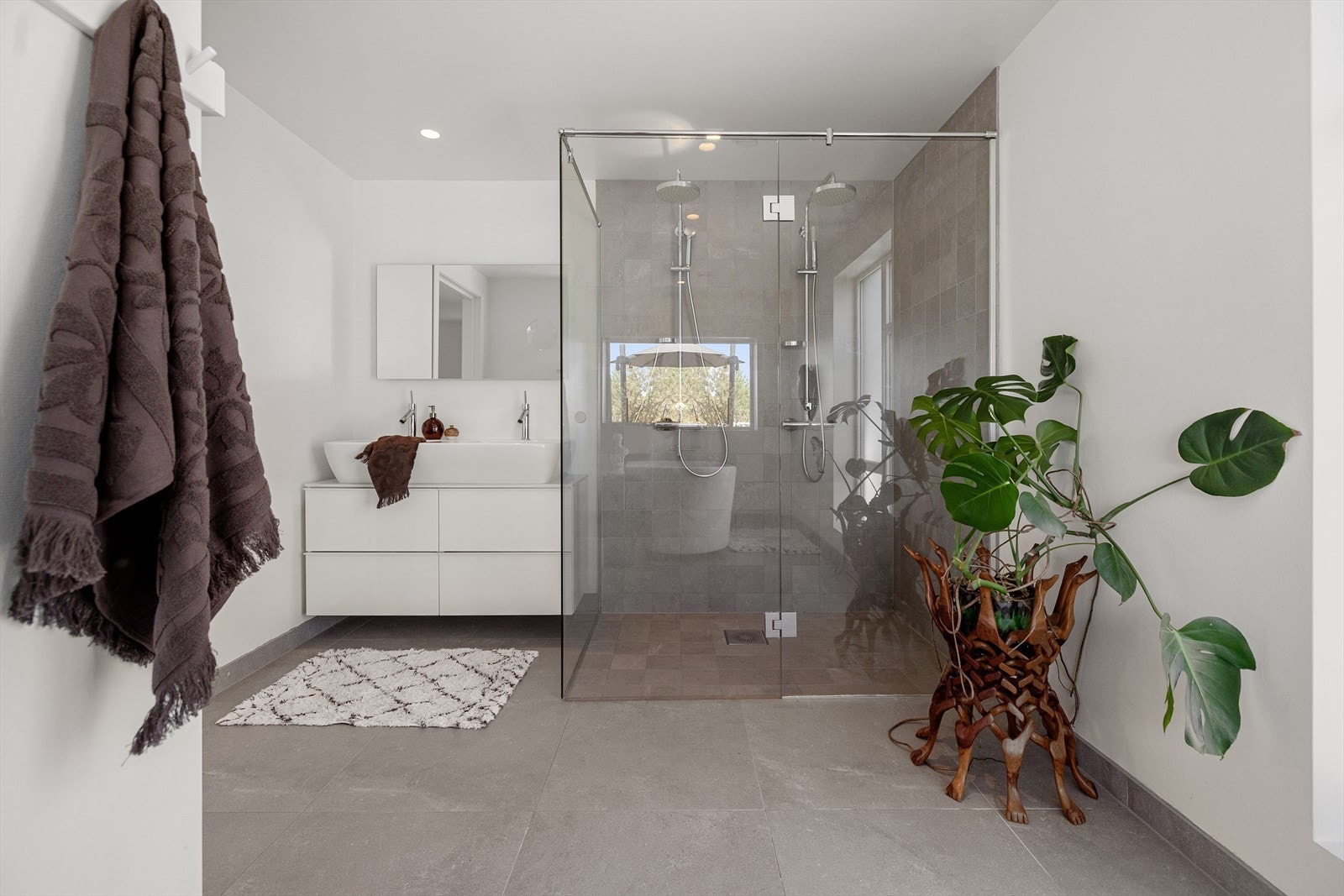 Baderommet har slette vegger kledd i strie, slett hvitt tak med downlights og grå naturfliser. Galleribilde