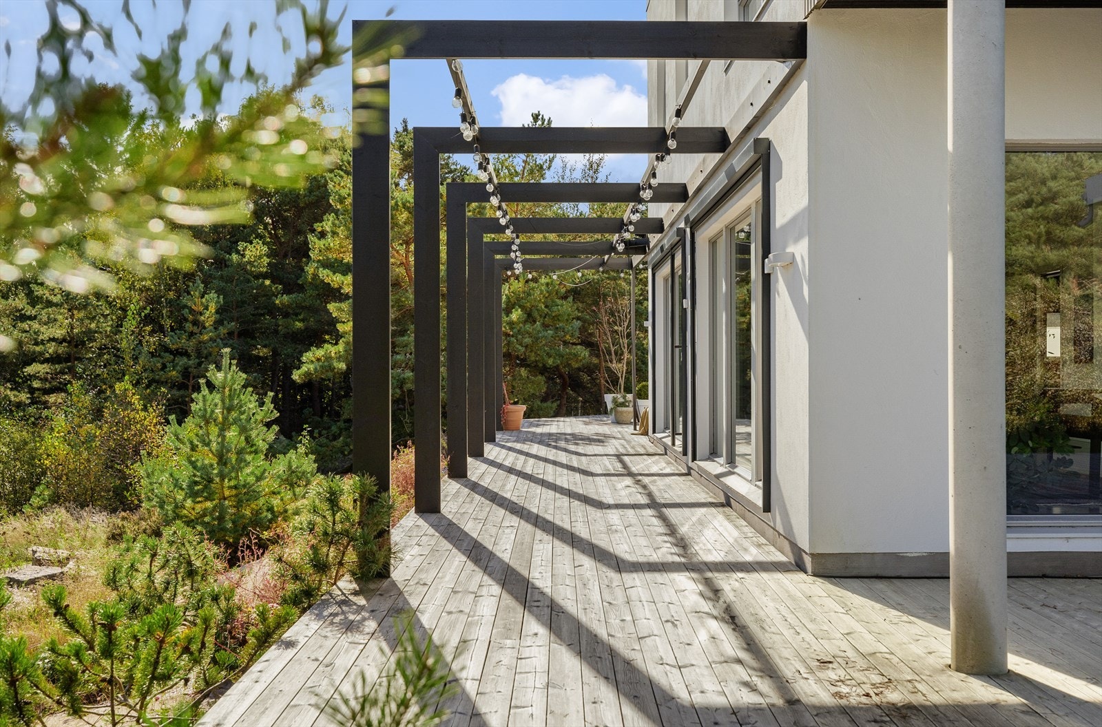 Fra takterrassens søyler tegnes det opp små rom og soner akkurat som de nyoppførte, sorte pergolaene gjør på boligens bakside. Galleribilde