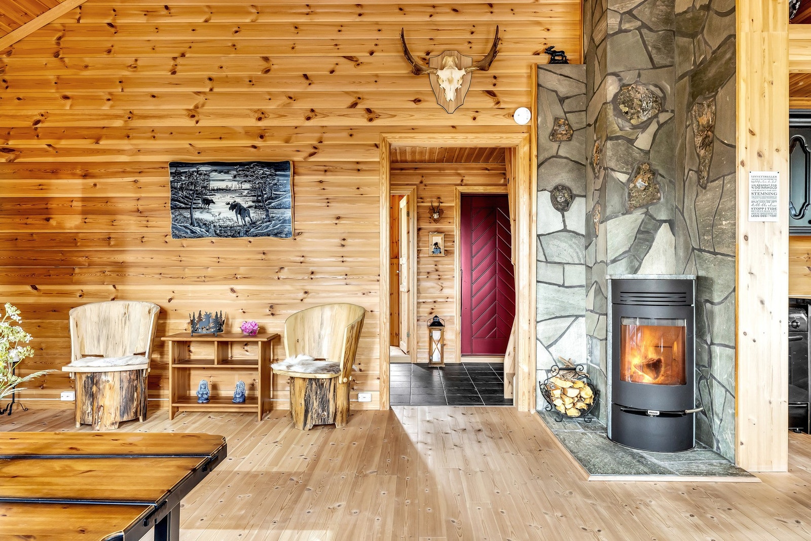 Stuen er lagt med heltre furugulv og tømmerpanel på veggene. Peisen er rommets blikkfang med murt pipe kledd i skiferstein og gir rommet lun og god varme på kalde kvelder. Galleribilde