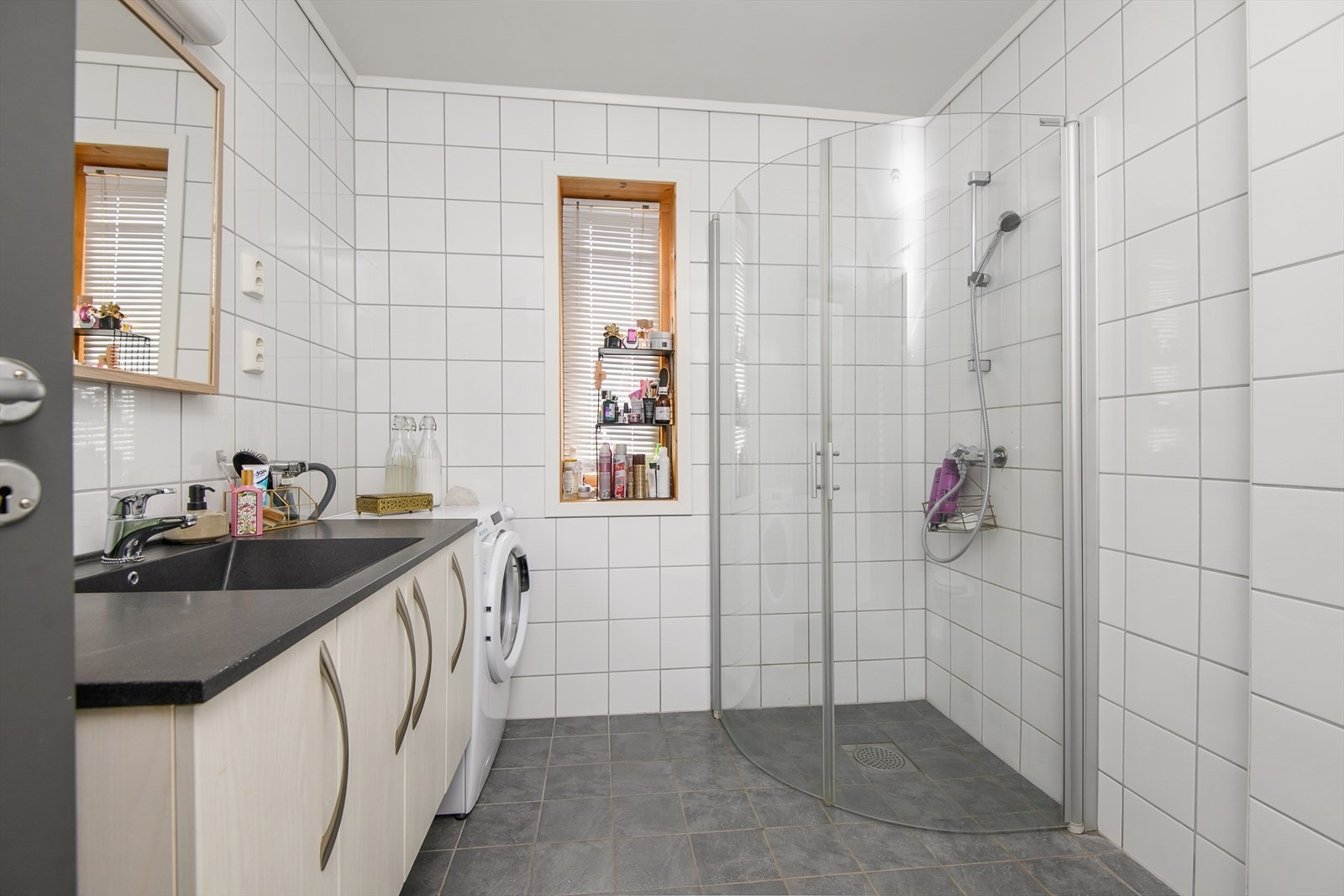 Tidløst, flislagt bad/wc har dusjhjørne og servantinnredning. Galleribilde