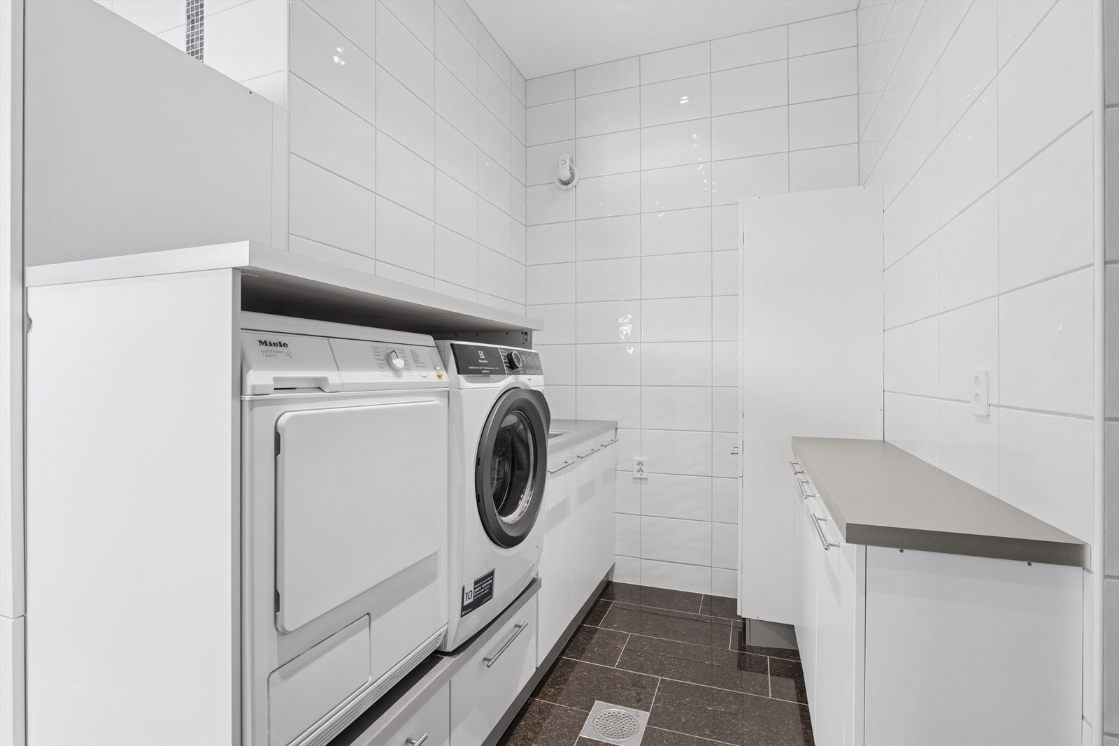 Helfliset vaskerom med god benkeplass og opplegg til vaskemaskin og tørketrommel. Galleribilde