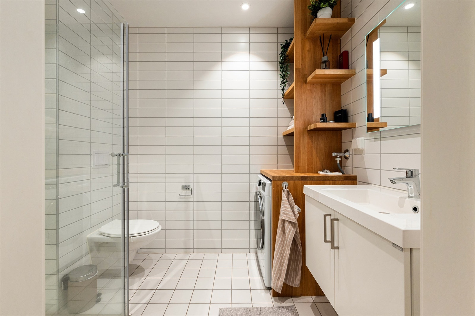 Badet er pent flislagt på gulv og vegger med varme i gulvet. Badet har dusjhjørne med svingbare glassdører og vegghengt toalett. Galleribilde