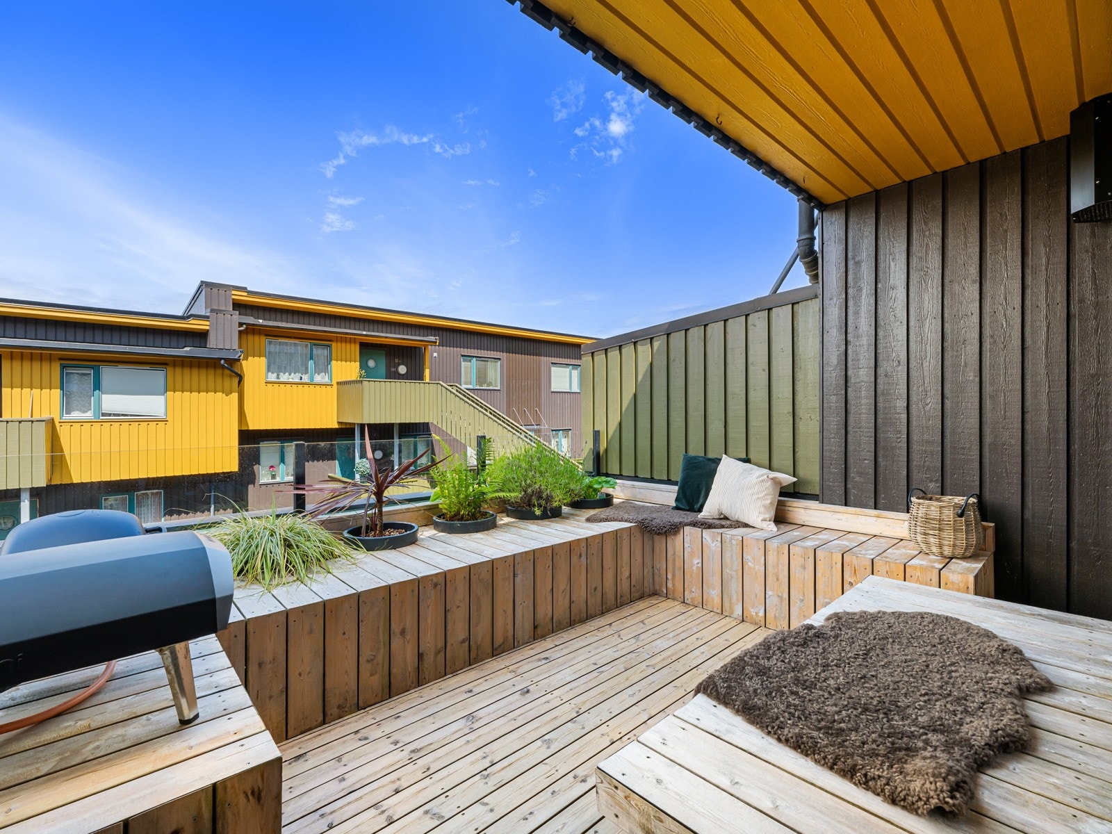 Stilig, solrik terrasse med stedbygde benker med nedfelte blomsterpotter Galleribilde