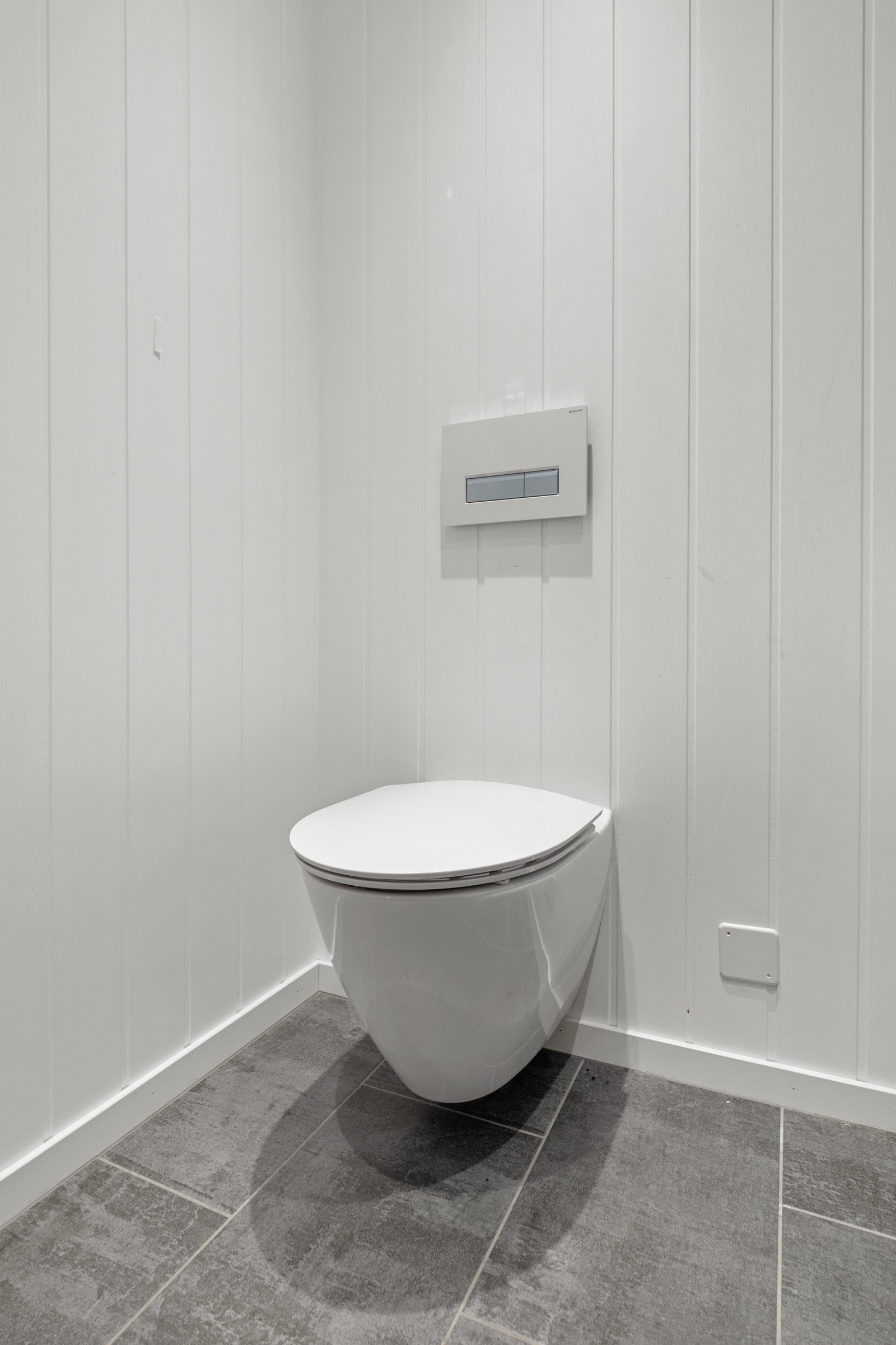 Rommet har fliser på gulv, lysmalte panelvegger og pen innredning. Galleribilde