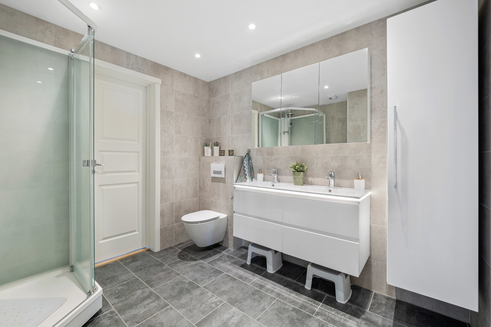 Badet har flislagte vegger og gulv, varmekabler i gulvet og downlights i taket. Galleribilde