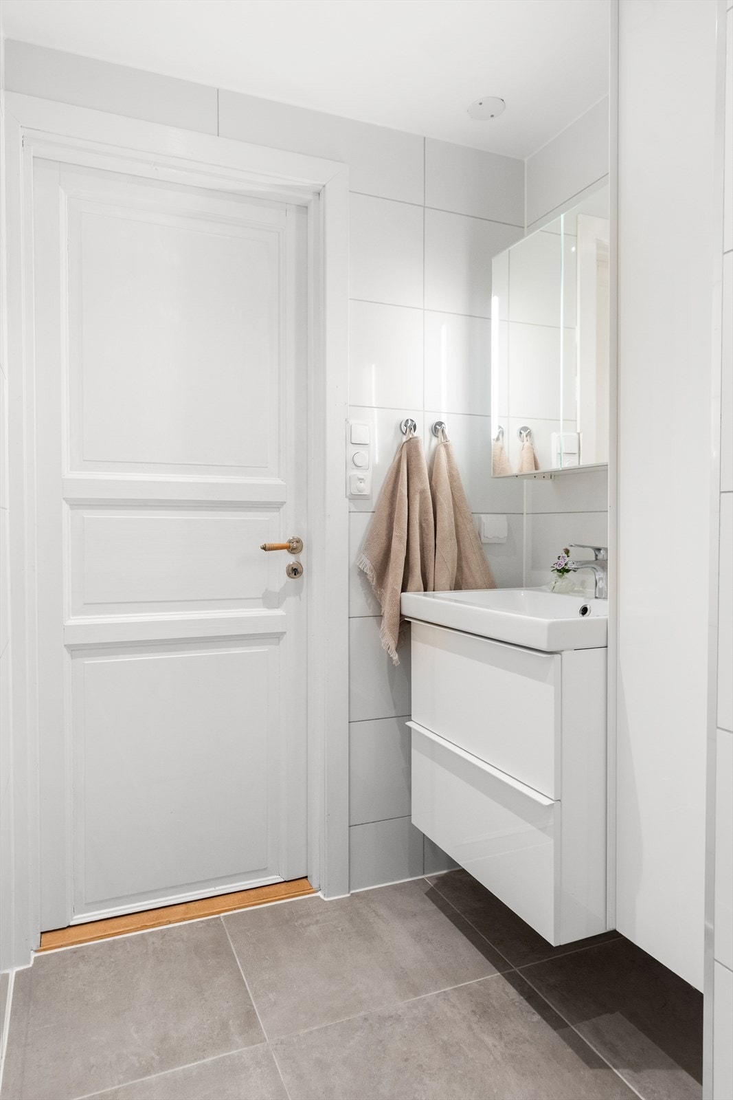 Badet er innredet med servant med underskuffer, speilskap med integrert belysning, vegghengt toalett, dusj med glassdører og opplegg for vaskemaskin. Galleribilde