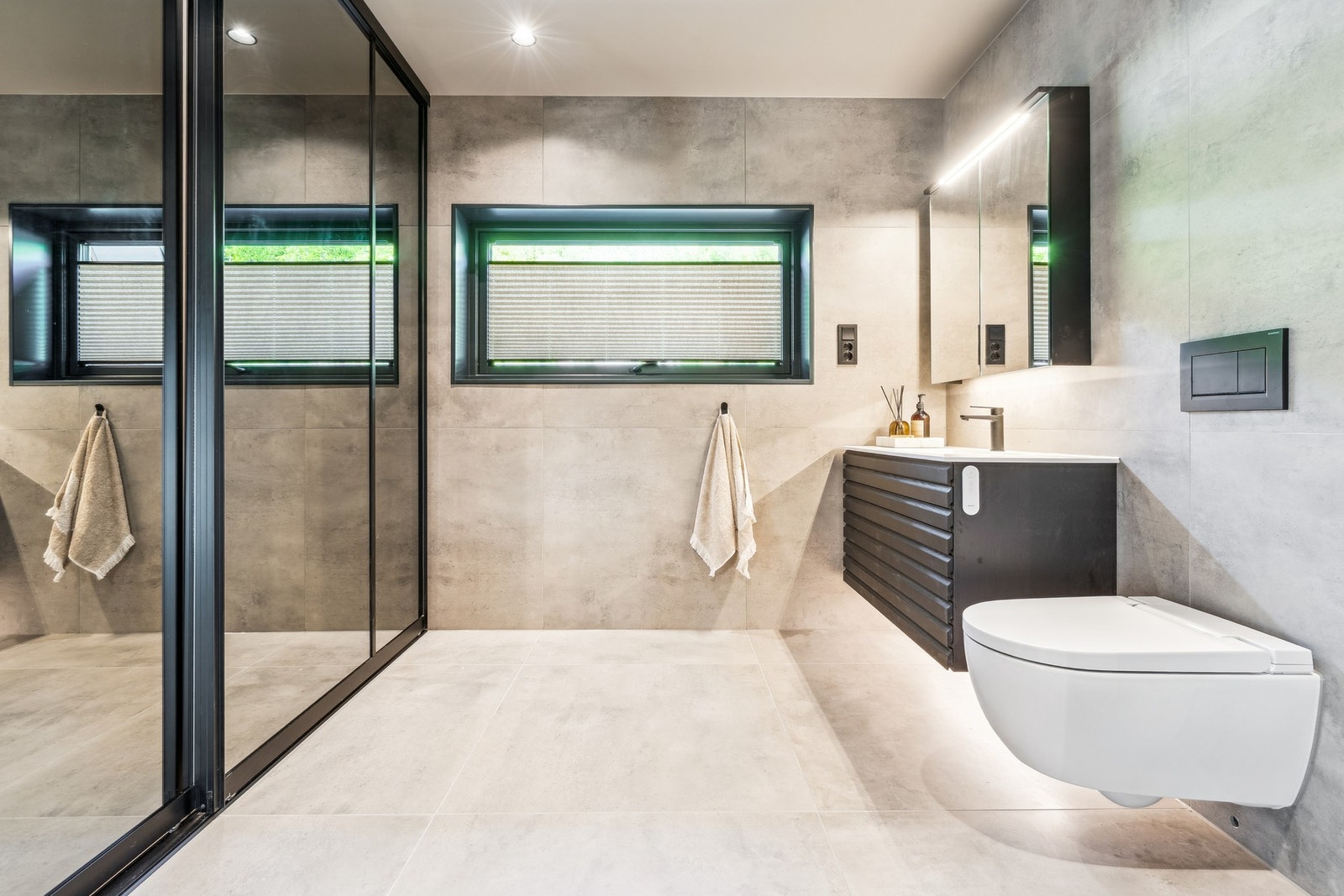 Moderne bad med skyvedørsgarderobe med egen innredning, utslagsvask og opplegg for vaskemaskin. Galleribilde