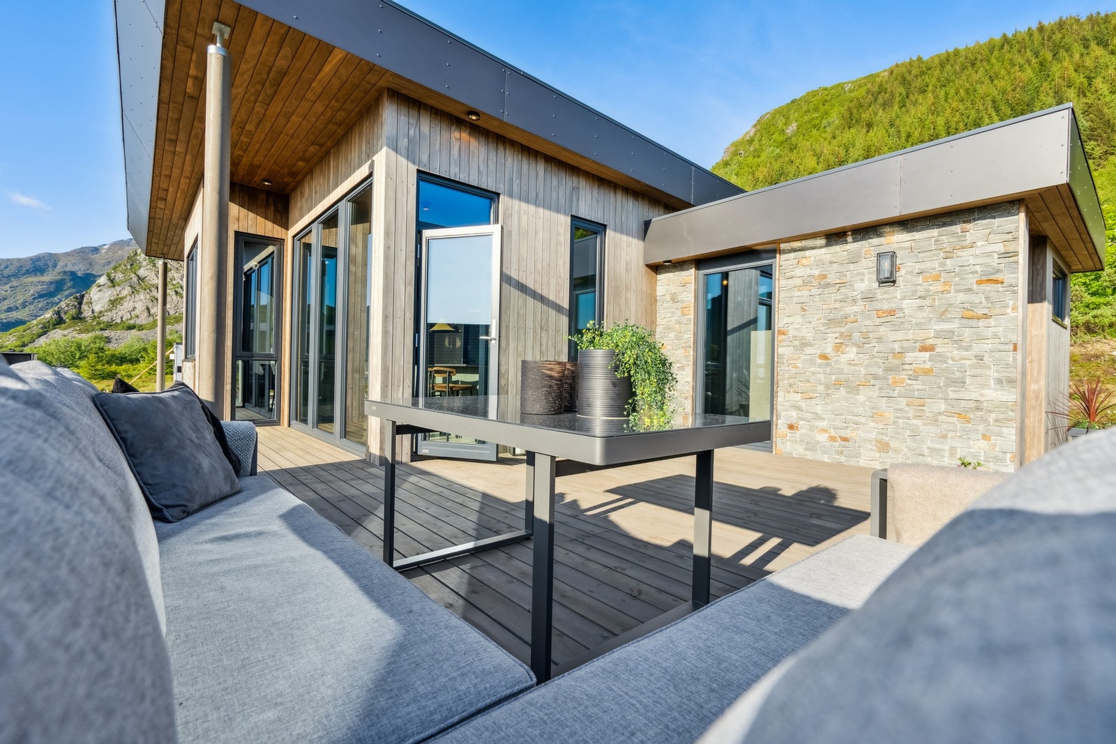 Utvendig kledning er en kombinasjon med plater, stein og dobbelfals kledning. Downlights i tak utvendig og flere utelamper på vegg. Galleribilde