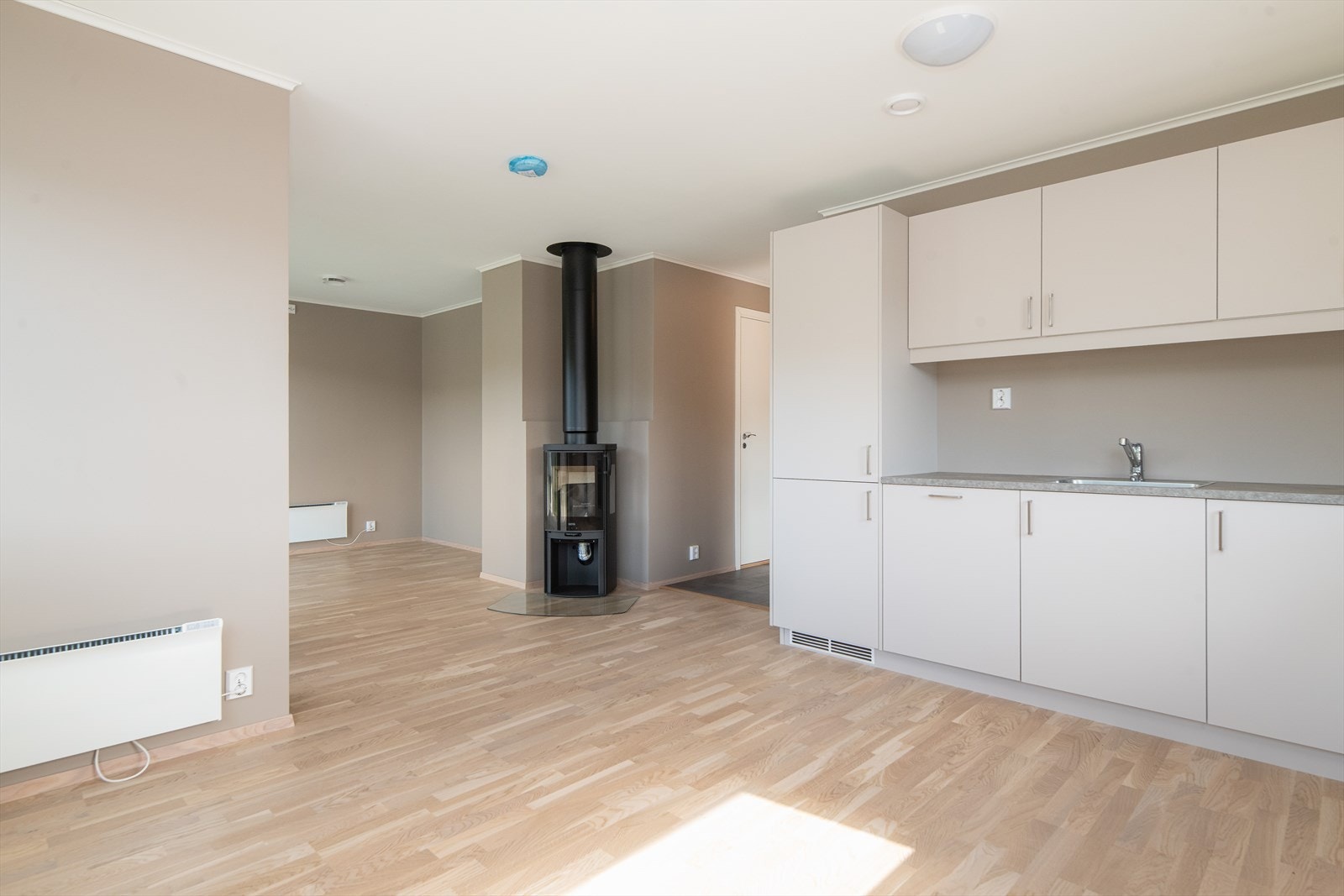 Åpen stue/kjøkkenløsning. Det er installert vedovn som gir varme og kos på de kaldeste vinterdagene. Galleribilde