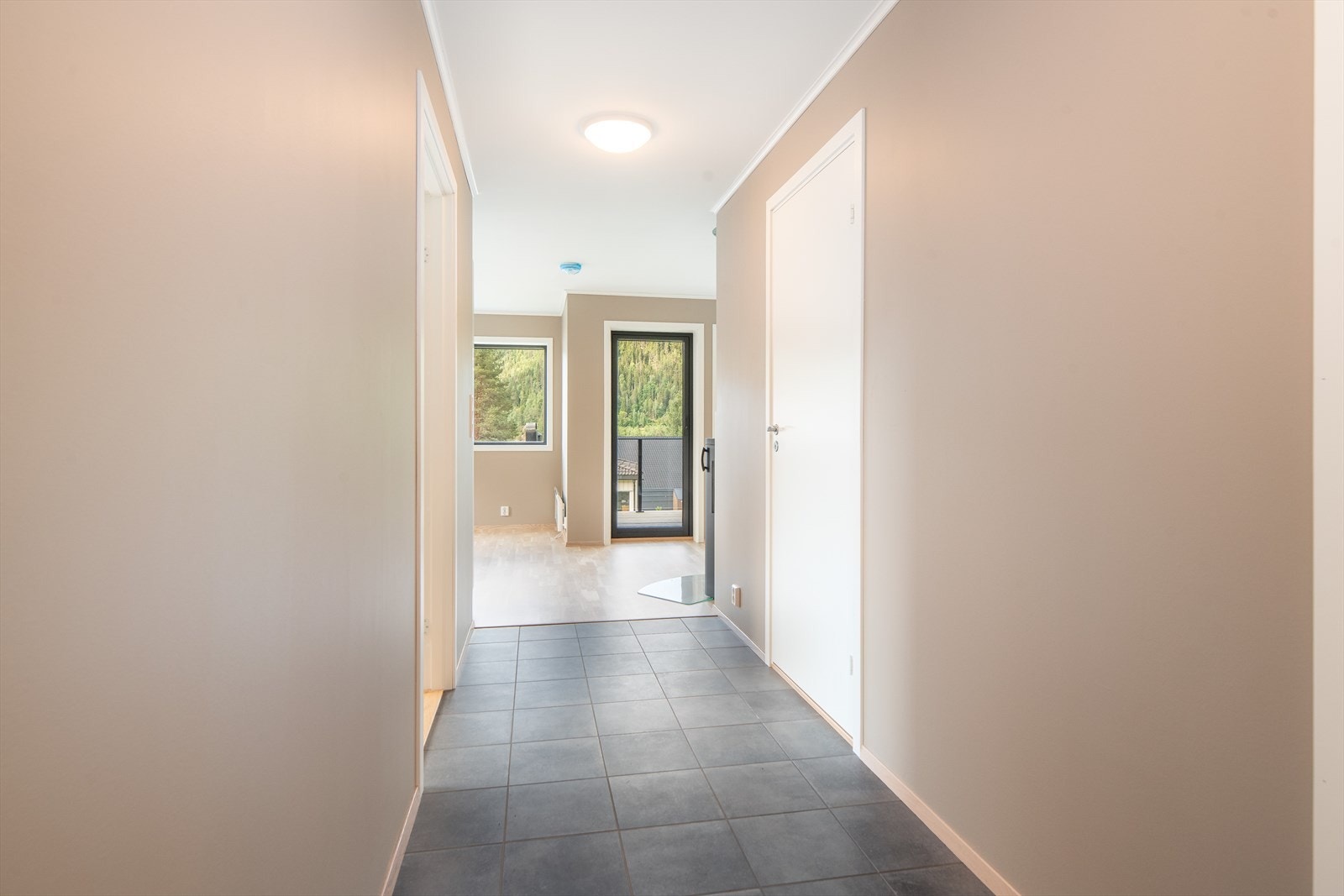 Allerede fra inngangspartiet ser man det fine lyset fra vindusflatene i oppholdsrommene. Gangen har flislagt gulv med varmekabler Galleribilde