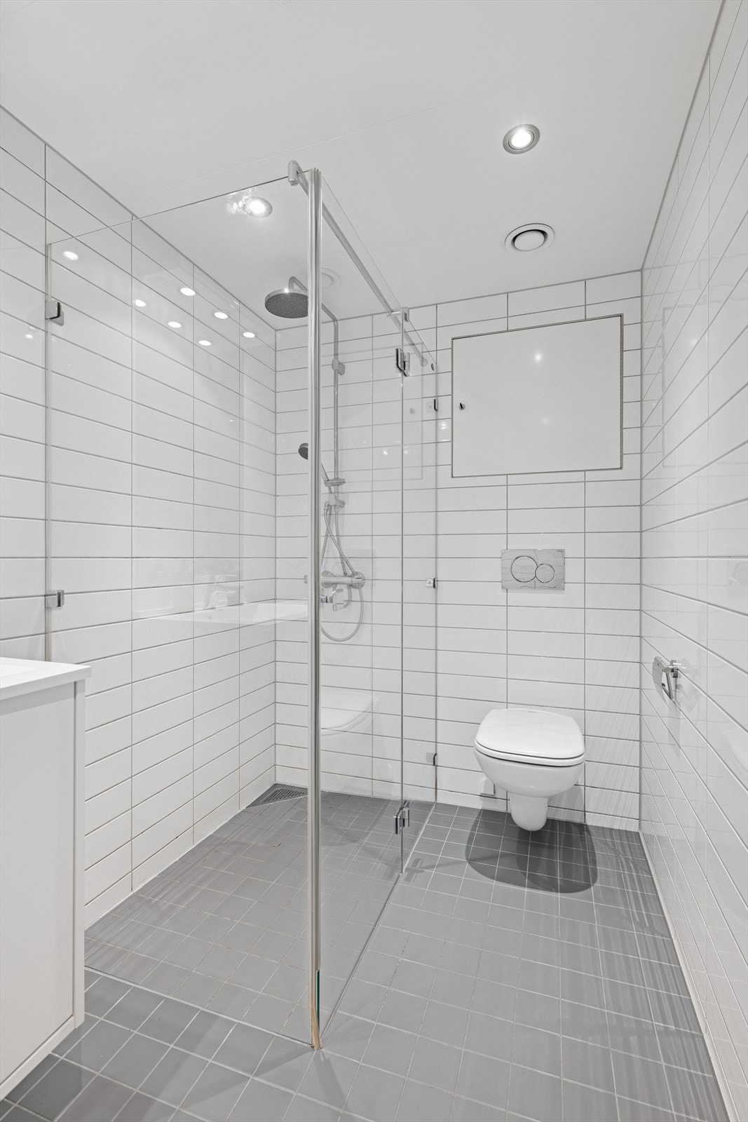 Lekkert og moderne bad med rene linjer, store fliser og et svært romslig dusjløsning - et rom som kombinerer stil med funksjon. Galleribilde
