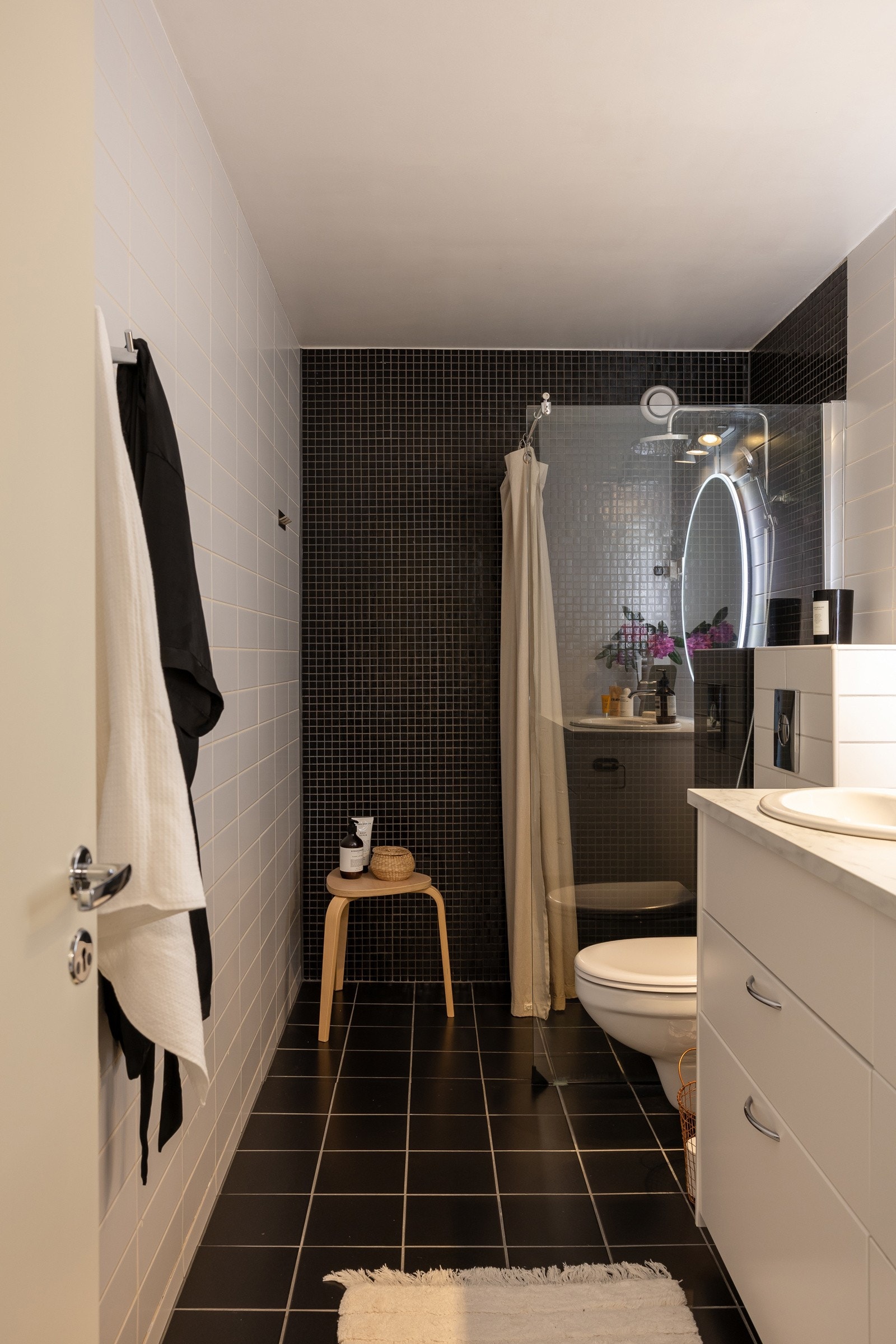 Delikat baderom med fliser på gulv og vegger, samt slettmalt tak. Varmekabler i gulv sørger for god komfort, og rommet er utstyrt med vegghengt toalett, dusjnisje og opplegg for vaskemaskin. Galleribilde