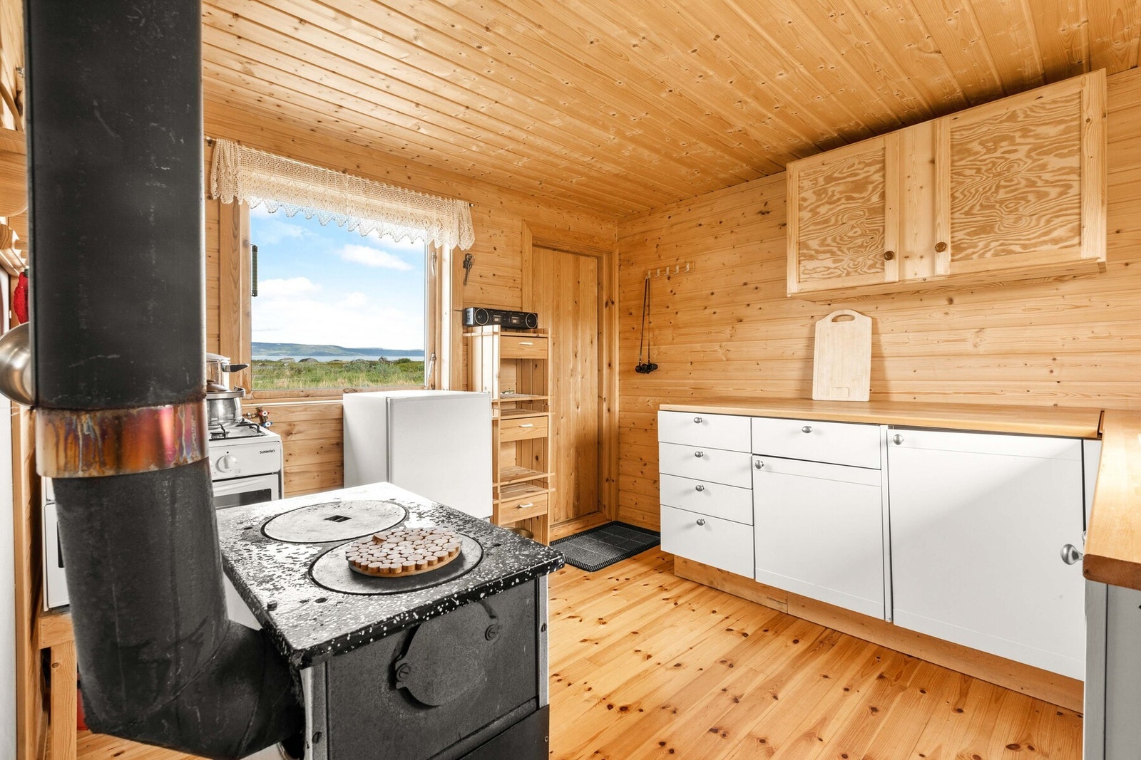 Kjøkkenet har god benk- og skapplass i kjøkkeninnredning med hvite fronter Galleribilde