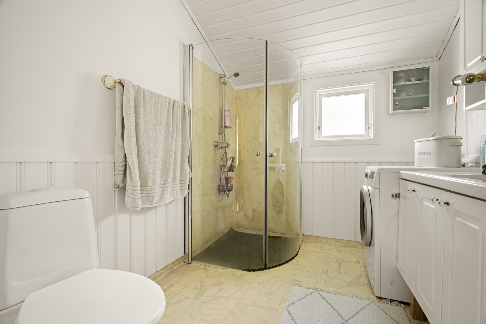 Vanlig standard på baderomsinnredning som består av vask, klosett, dusjhjørne og avløp til vaskemaskin Galleribilde