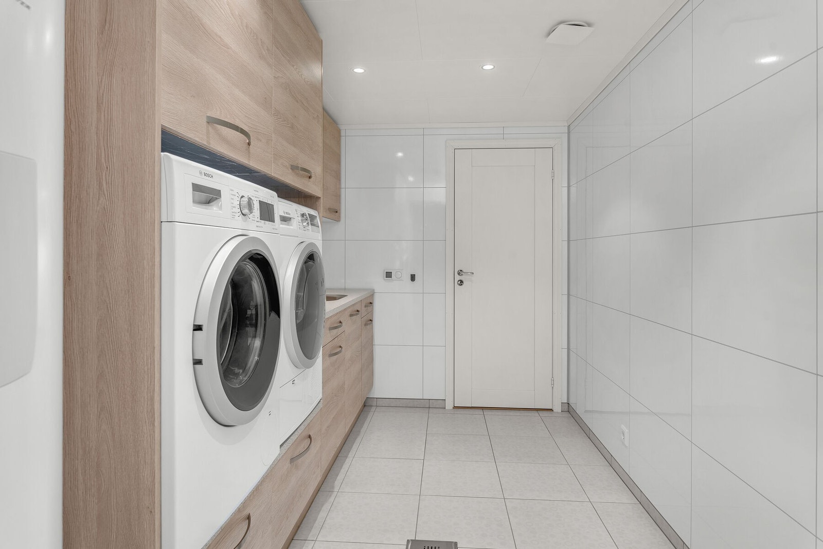 Separat vaskerom med praktisk innredning for vaskemaskin og tørketrommel. Rikelig med oppbevaringsplass. Galleribilde