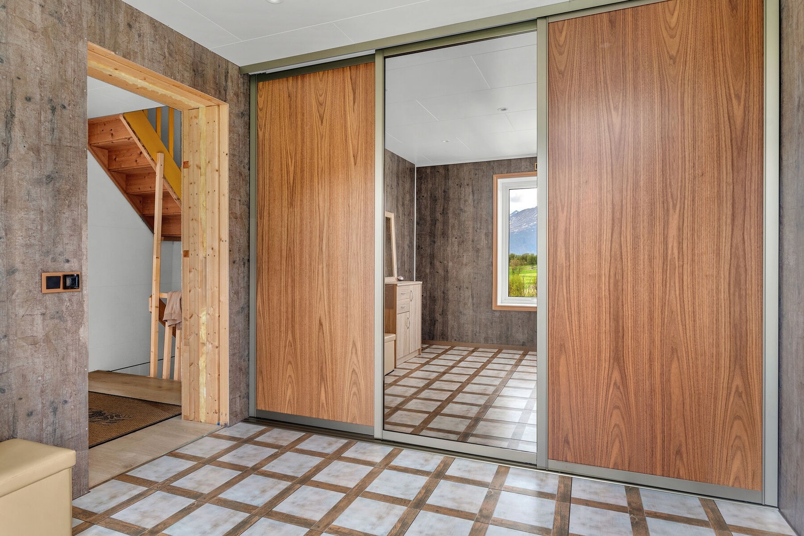 Romslig entré med skyvedørsgarderobe og flislagt gulv. Galleribilde