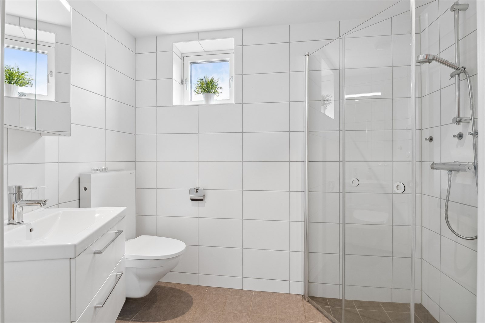 Privat baderom for hovedsoverommet som er gjennomført med flotte fliser i moderne fargetoner på vegger og gulv. Det er elektriske termostatstyrte varmekabler i gulvet og vindu på vegg som slipper inn godt med naturlig dagslys. Galleribilde