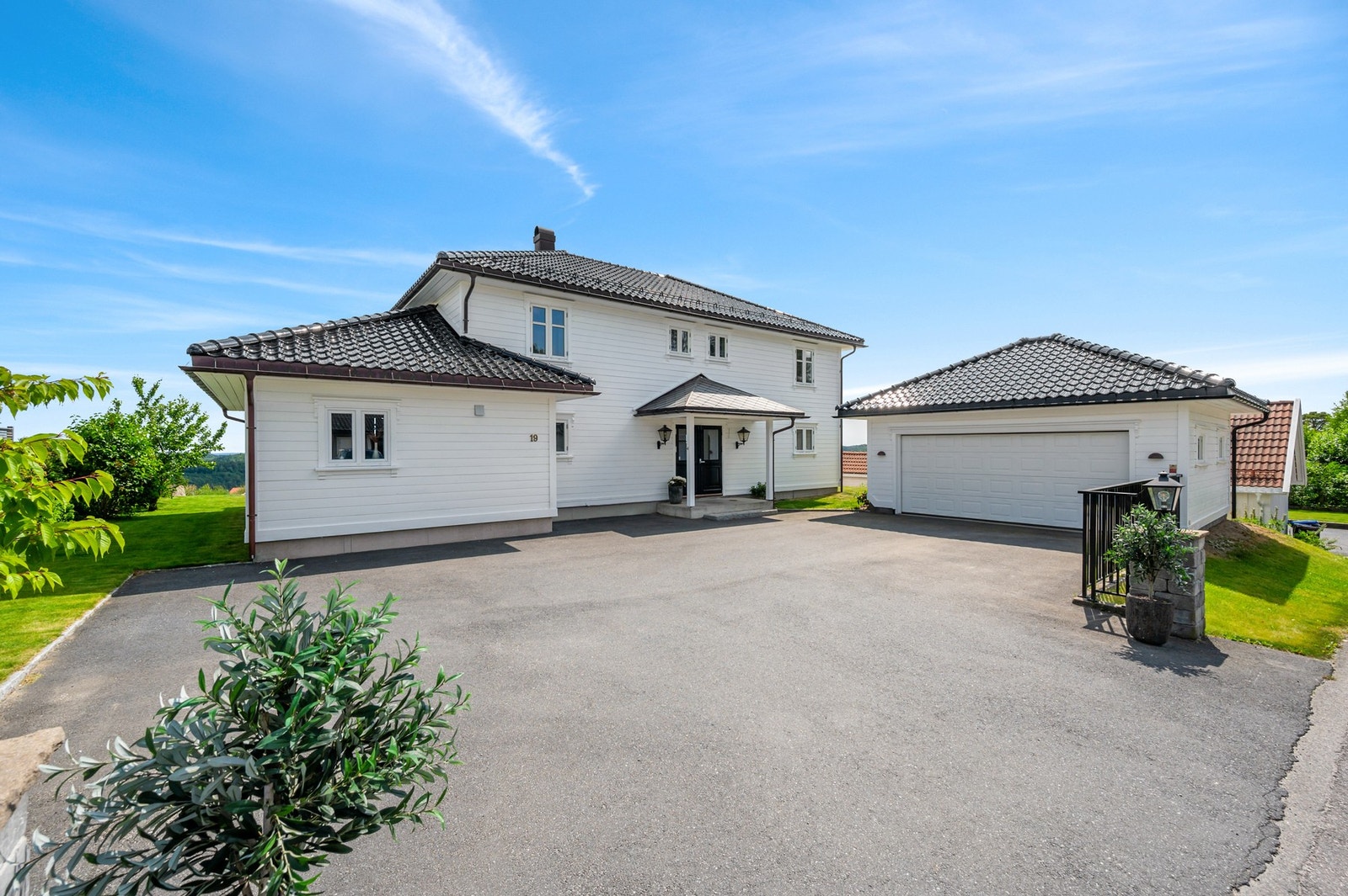 Tunet er asfaltert. Det står en romslig dobbelgarasje på eiendommen med elbil lader. Galleribilde