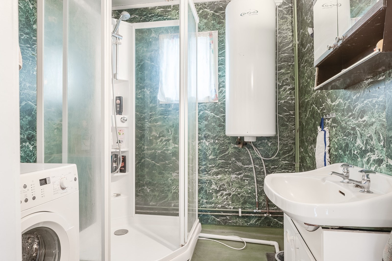 Eldre bad/vaskerom i leiligheten i 2. etasje med våtromsbelegg på gulv og våtromsplater på veggene. Galleribilde