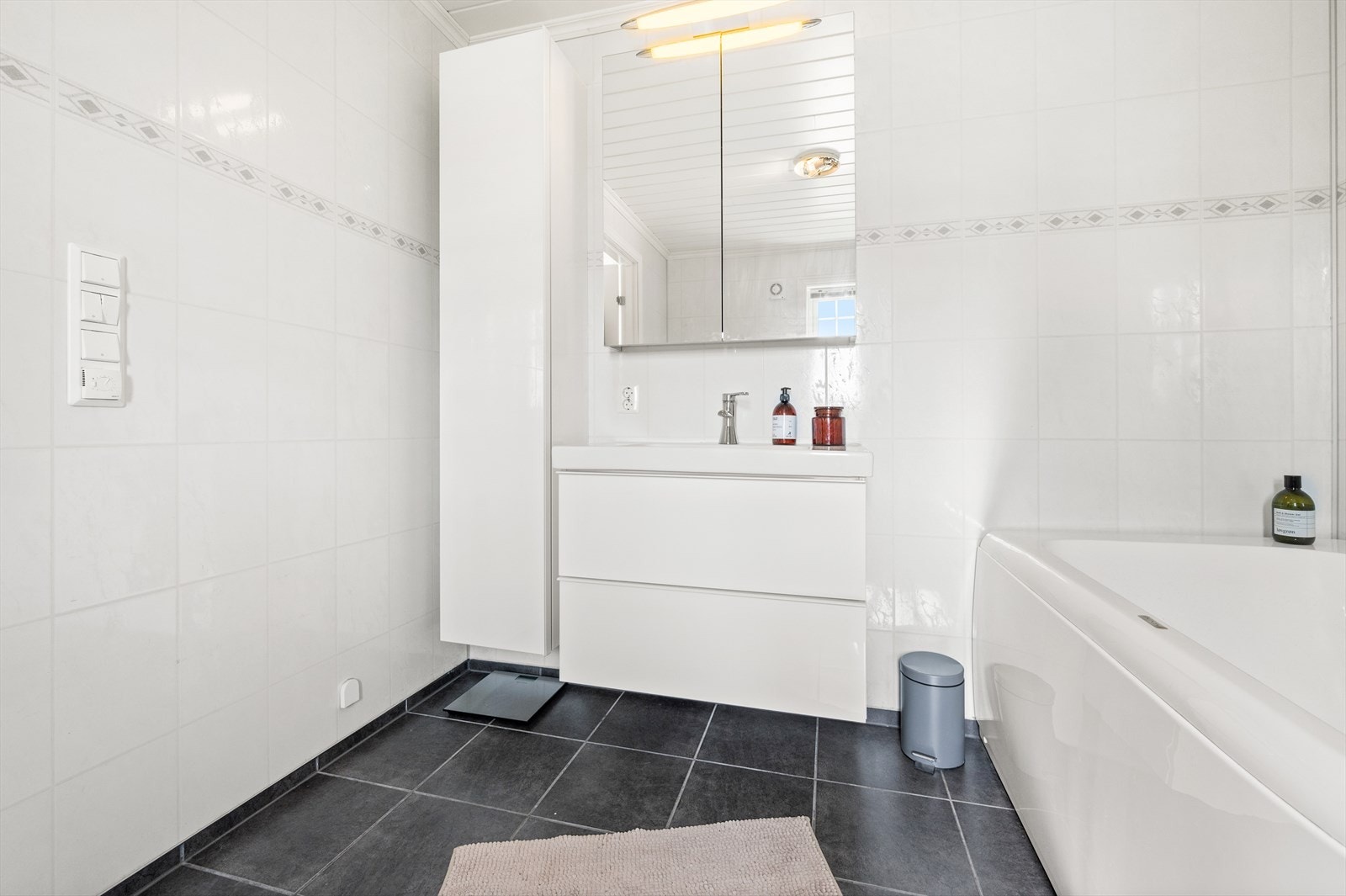 Lys baderomsinnredning med skuffer, heldekkende servant, speilskap. Høyskap på siden Galleribilde