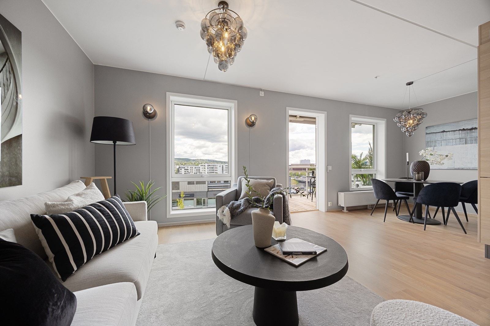 Lys og luftig stue med åpen løsning mot spiseplass og direkte utgang til balkong. Appstyrt lysskjerming gir fleksibel solkontroll. Galleribilde