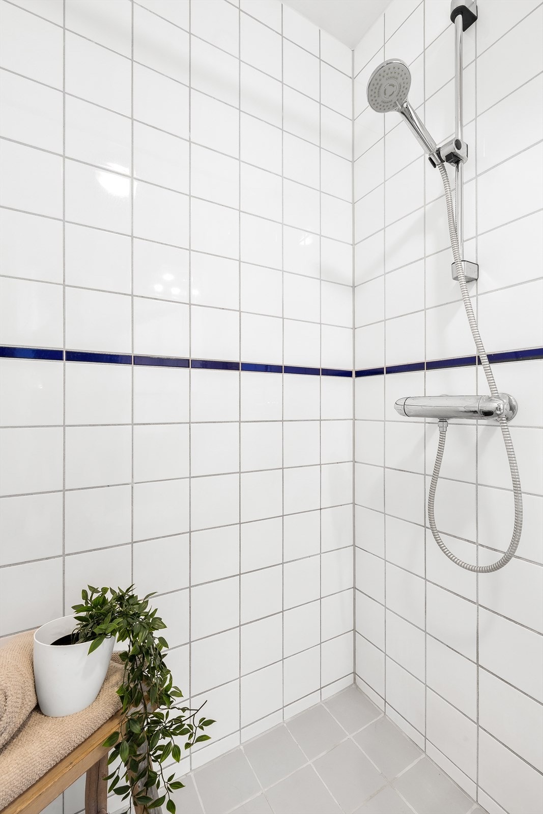 Badet er innredet med dusjhjørne med forheng, gulvmontert toalett, servant med underskap og overskap med speildører. Galleribilde