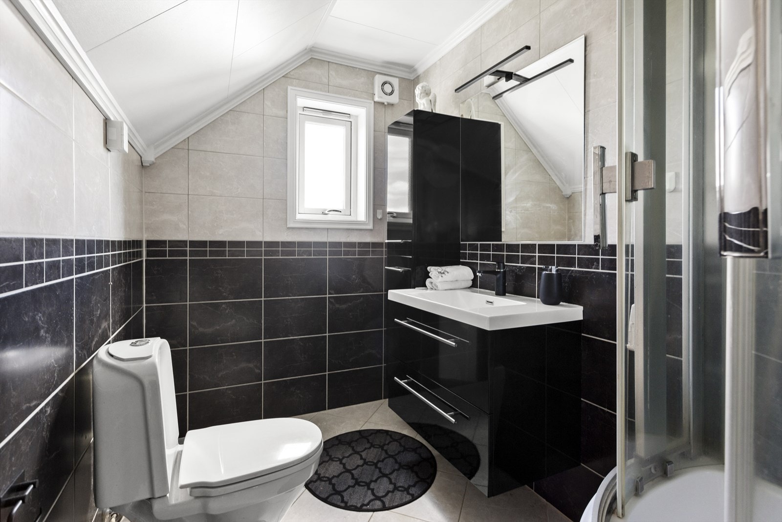 Badet i den 2. etasjen har sorte og lyse fliser på gulv og vegger. Galleribilde