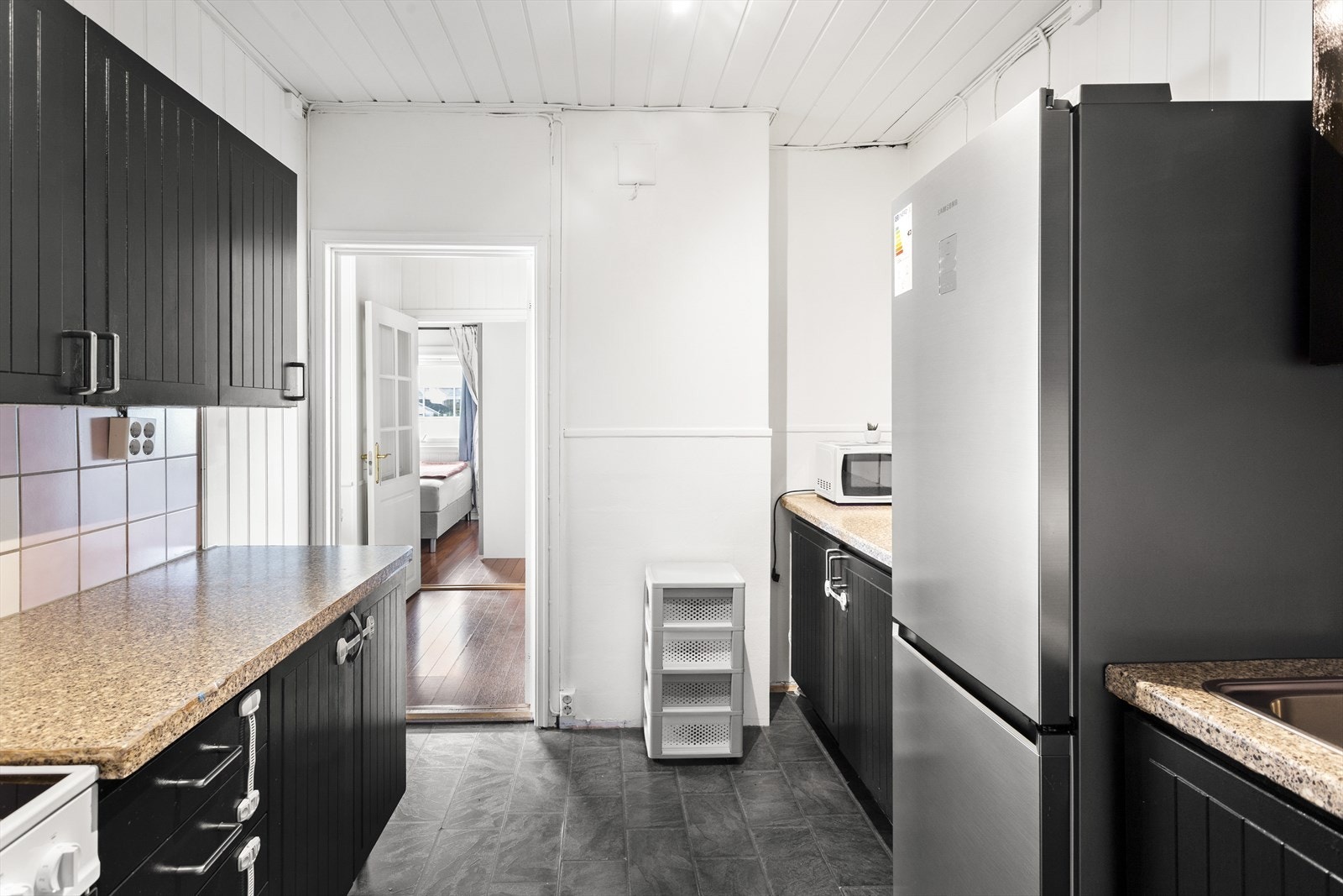 Kjøkkenet i 1. etasje har en sortmalt kjøkkeninnredning med laminert benkeplate og nedfelt oppvaskkum med 1-greps blandebatteri. Galleribilde