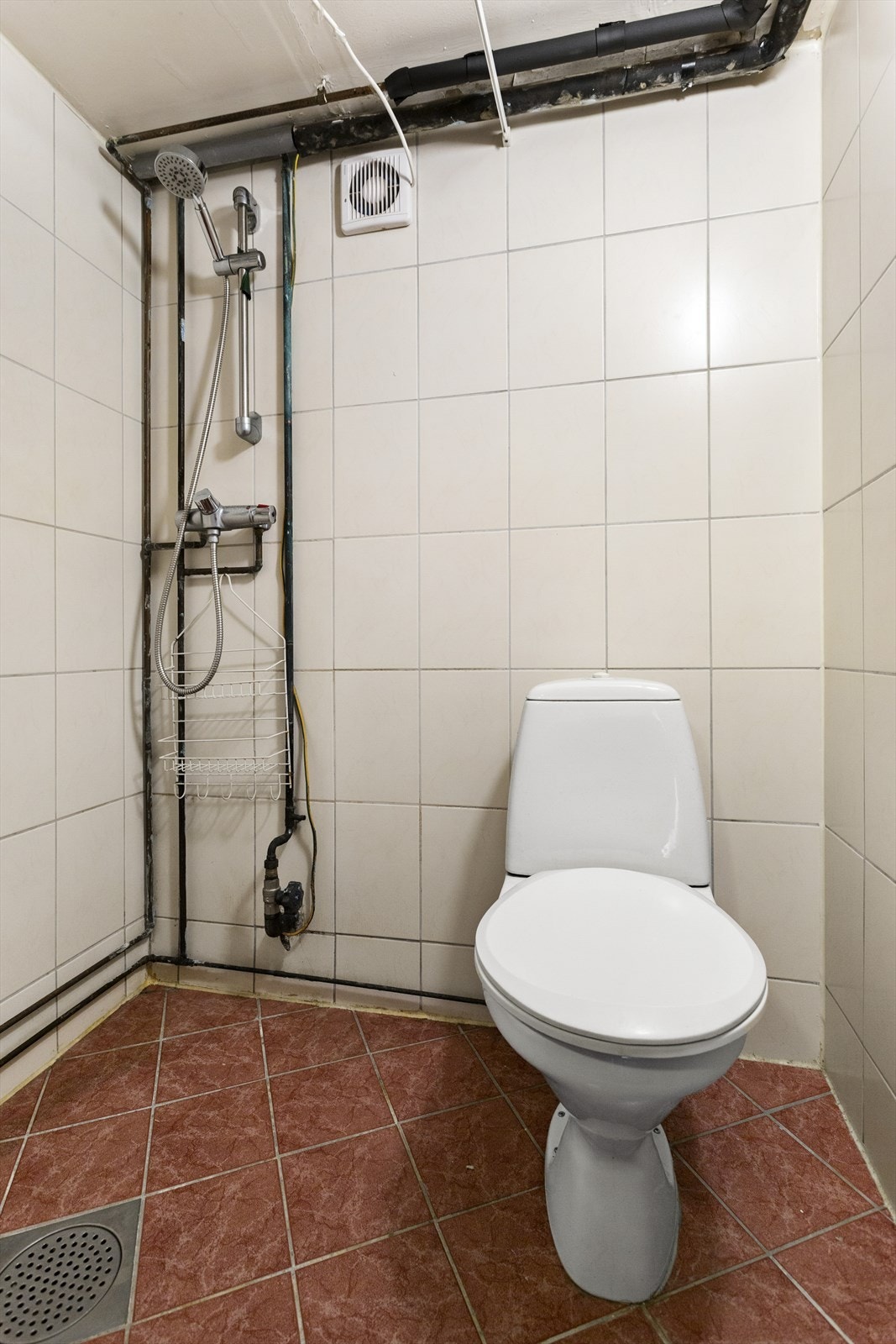 Her er det en dusjsone med dusjing direkte på gulv og vegg samt tilkoblet et vannklosett. Galleribilde